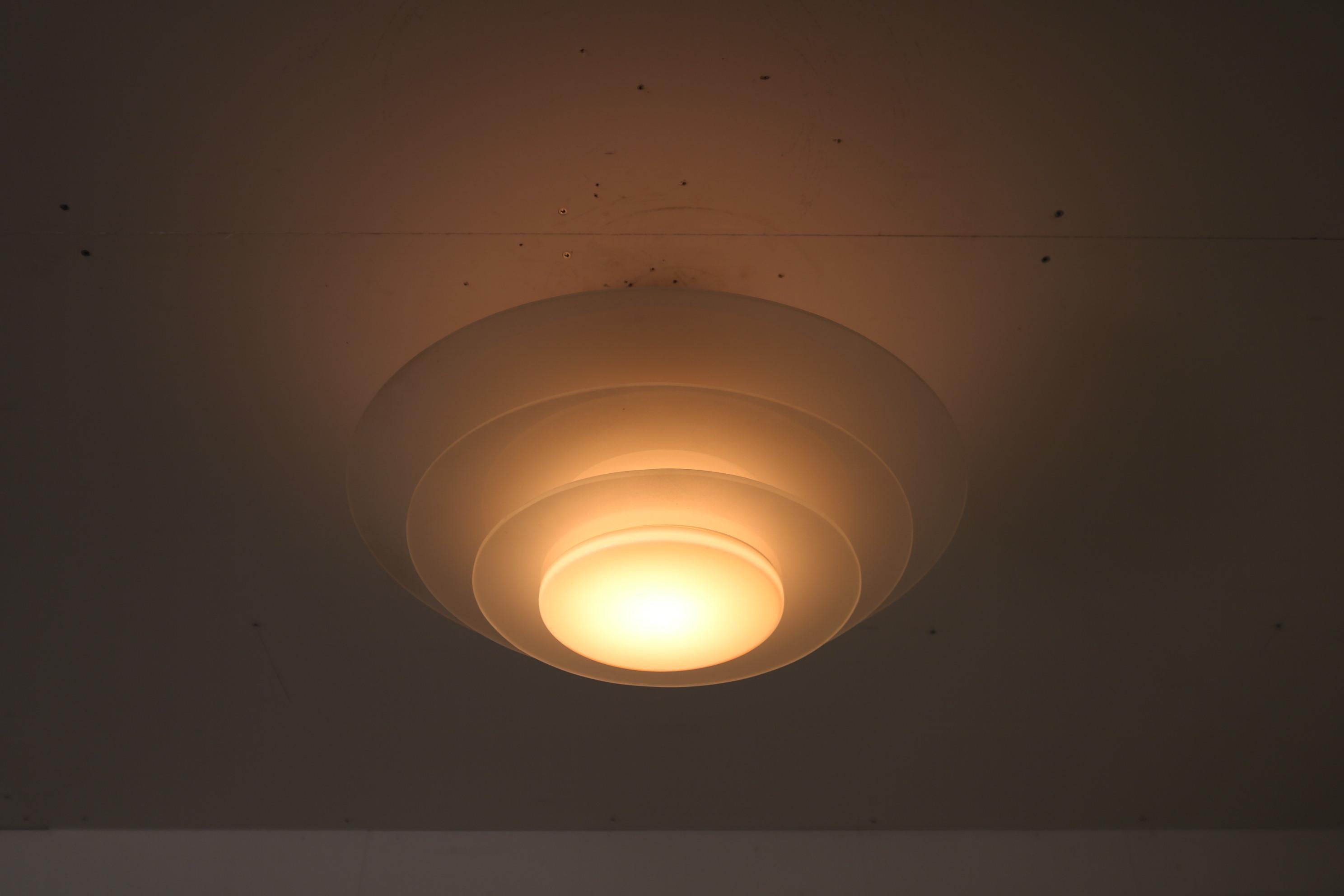 A wonderful ceiling lamp, manufactured by Bohlmarks in Sweden around 1930.

This eye-catching piece is made of several satin glass rings, beautifully layered and allowing a really nice, warm light to emit. The light is nicely diffused by the cream