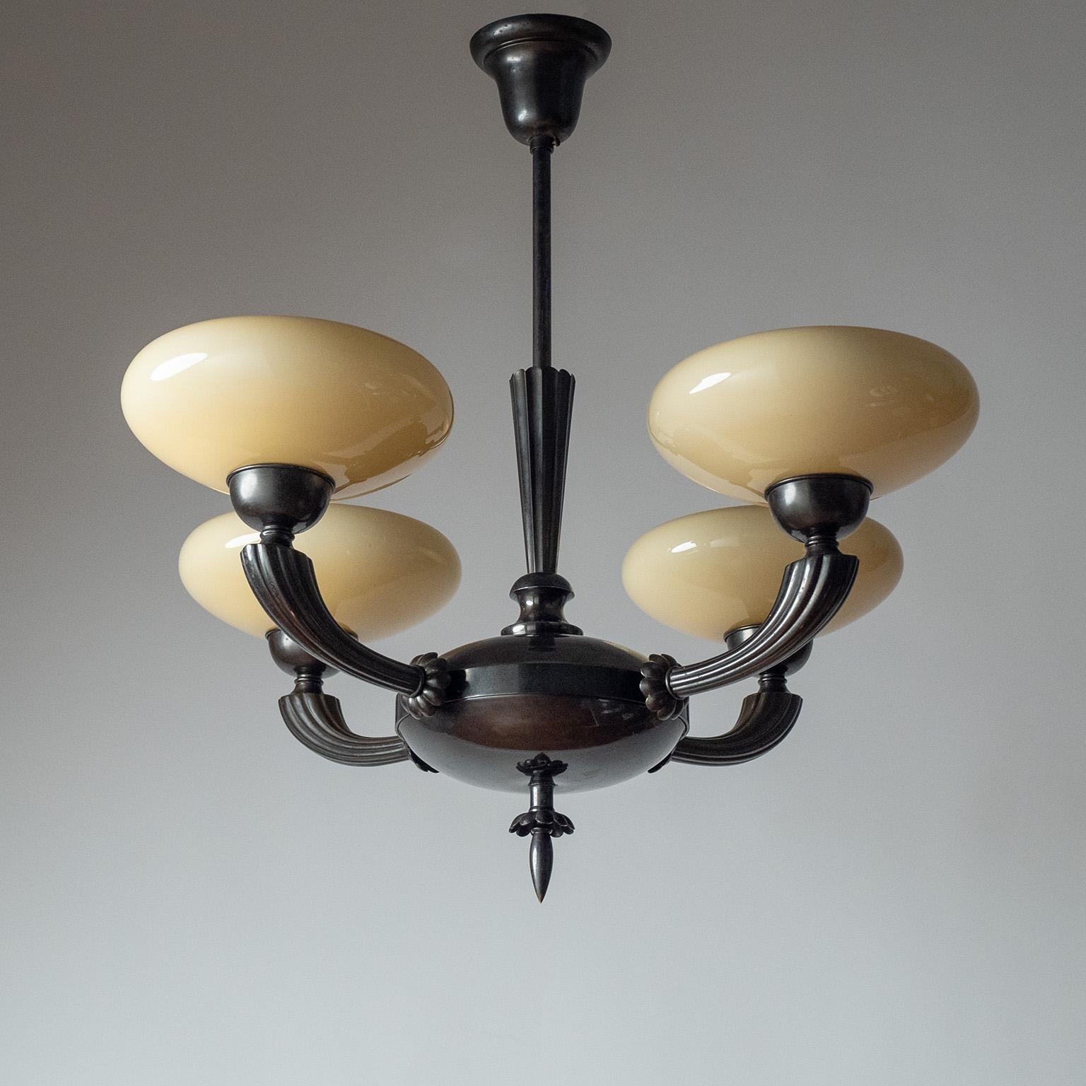 Raro lampadario modello 6353 disegnato da Harald Notini per Böhlmarks negli anni Trenta. Ottone patinato molto scuro con quattro paralumi in vetro color crema. Condizioni originali molto buone con una certa patina sull'ottone. Quattro prese e27