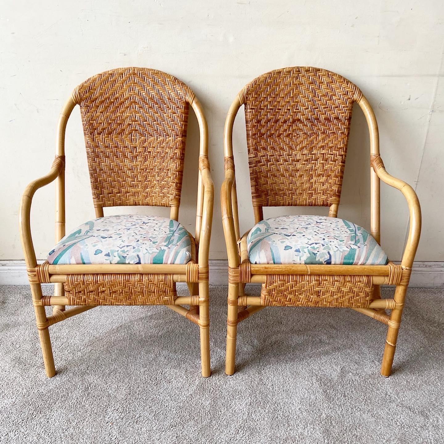 Amazing pair of vintage bohemian bamboo rattan and wicker arm chairs. Each feature a blue white and pink fabric seat cushion with a matching pillow.