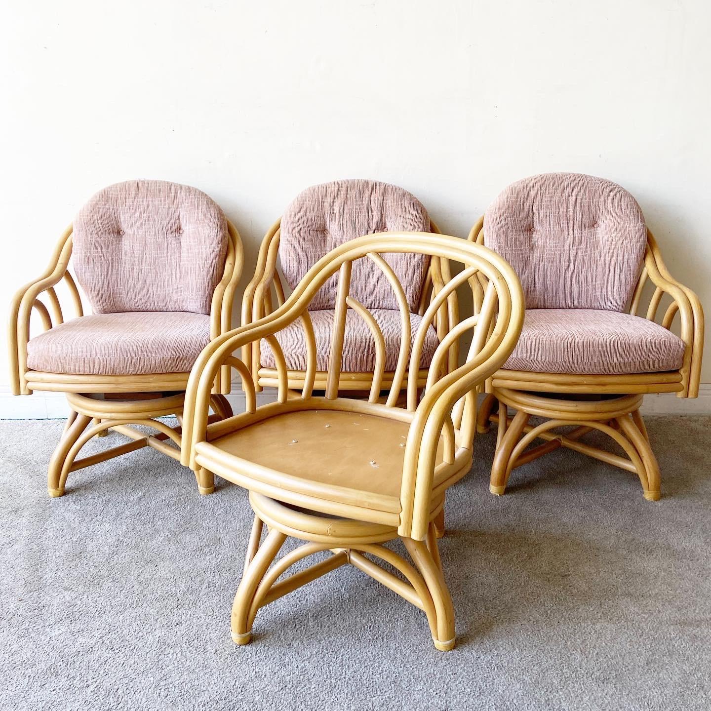 Amazing set of 4 bamboo rattan swivel chairs by Rattan Specialities. Each chair features the original pink seat cushions with tufted backrests.