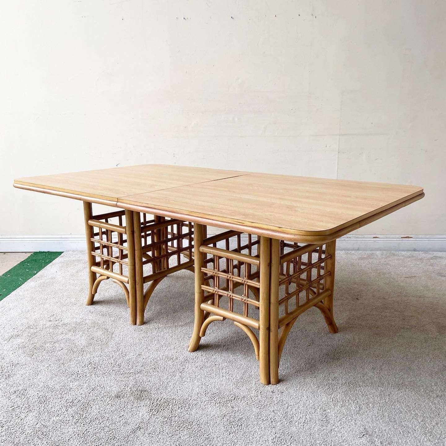 Exceptional vintage boho chic dining table. Features two bamboo rattan pedestals bases with a Woodgrain laminate top.