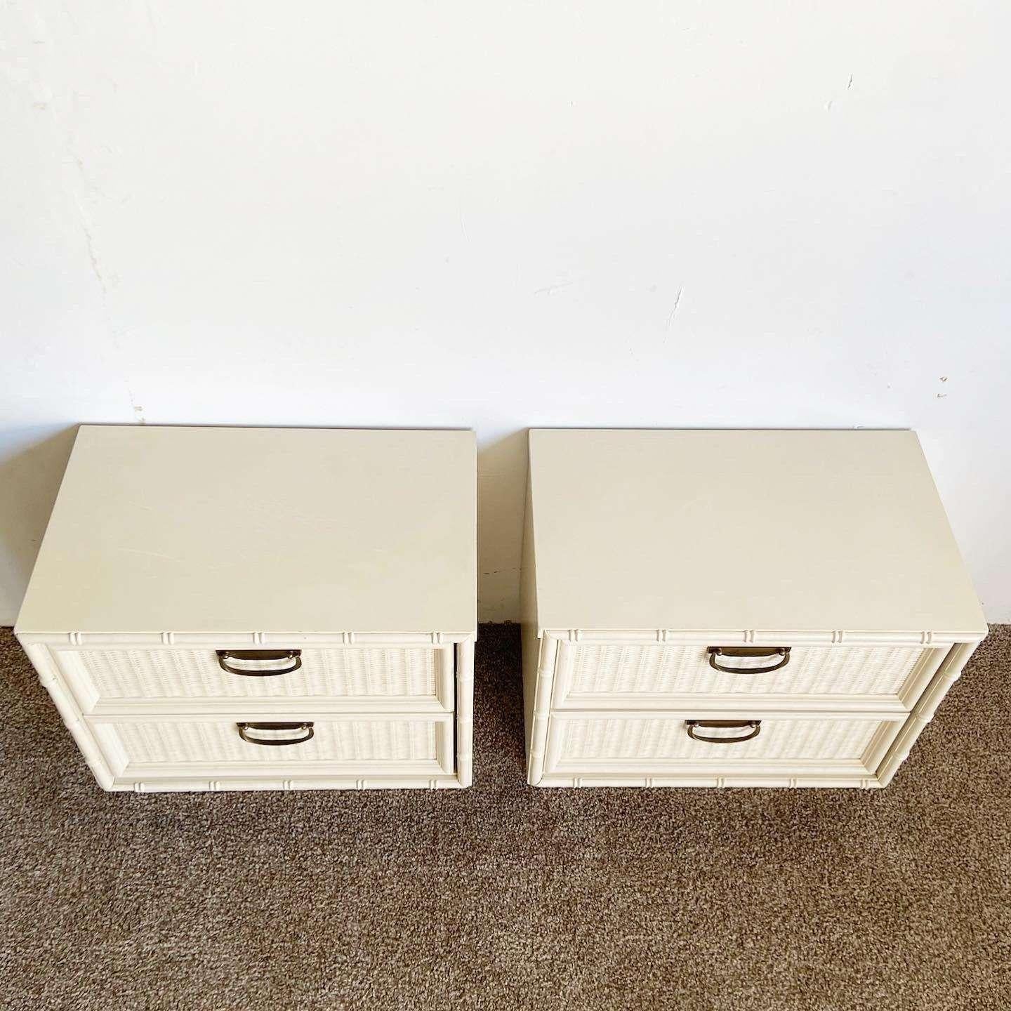 Incredible vintage bohemian pair of faux bamboo nightstands. Each feature faux wicker drawer faces with brass handles and an off white finish.