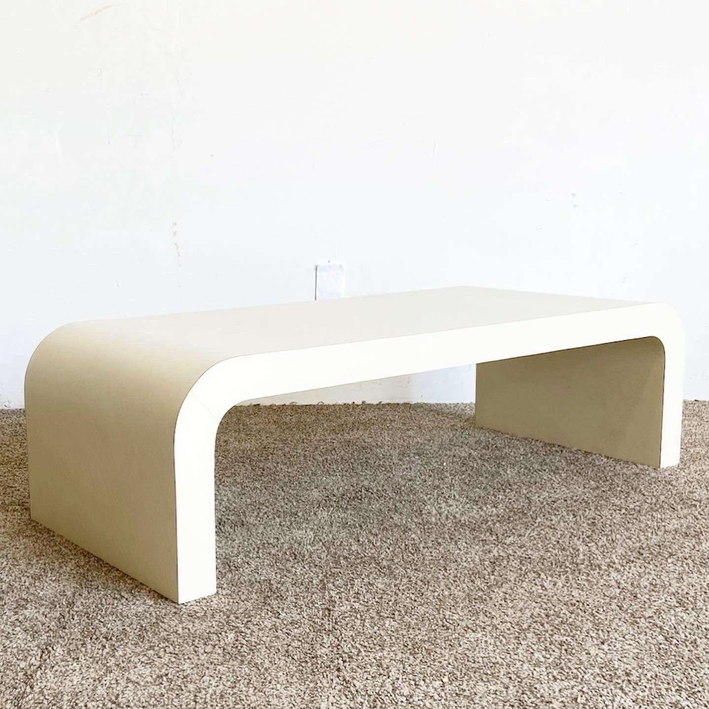 Exceptional vintage postmodern waterfall coffee table. Feature a textured faux leather cream laminate.