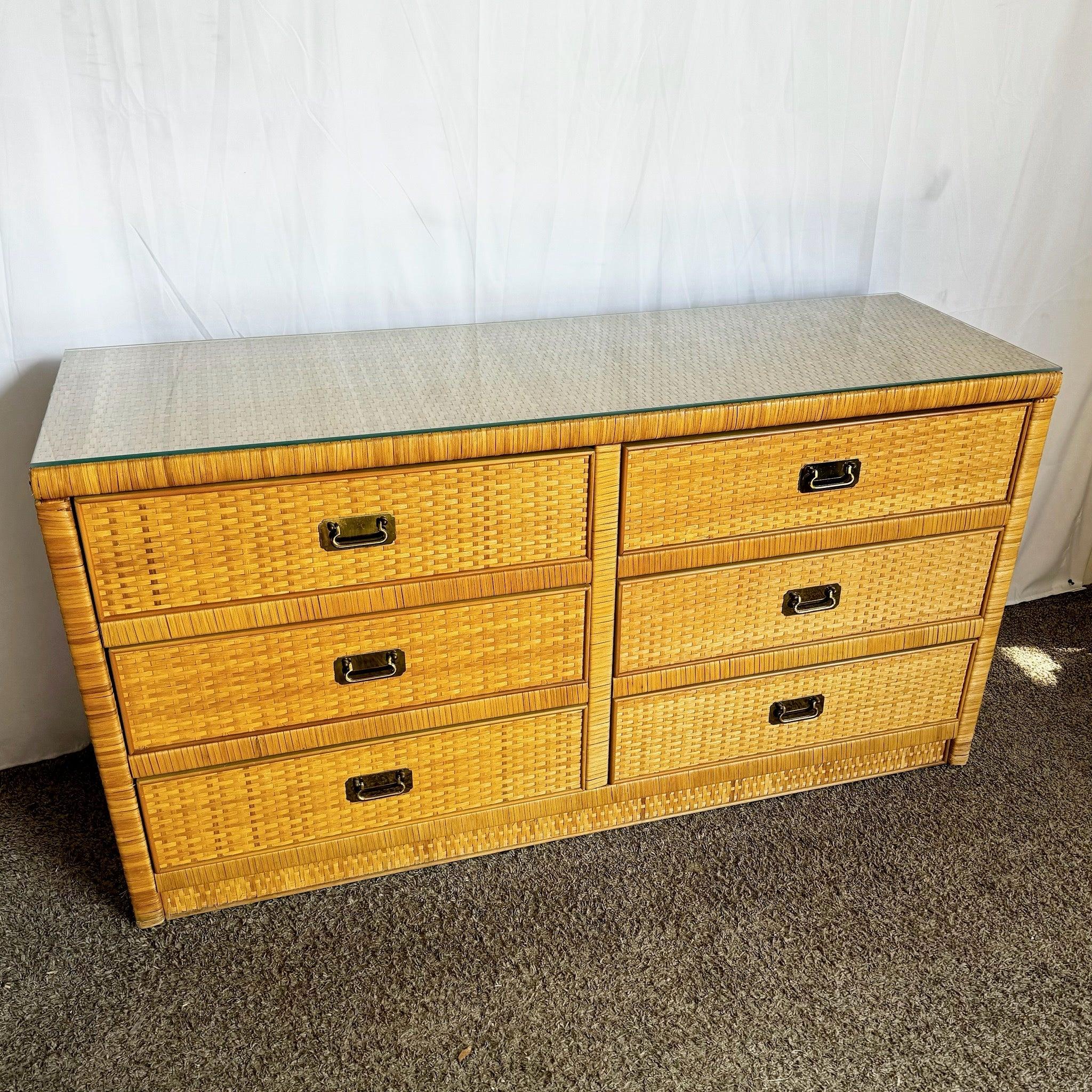 Boho Chic Glass Top Wicker Dresser with Brass Handles by Dixie, featuring six spacious drawers and a protective glass top, perfect for coastal-inspired interiors.
 
 A. Minor wear around the edges as shown in the photos and pitting to the brass.
 
