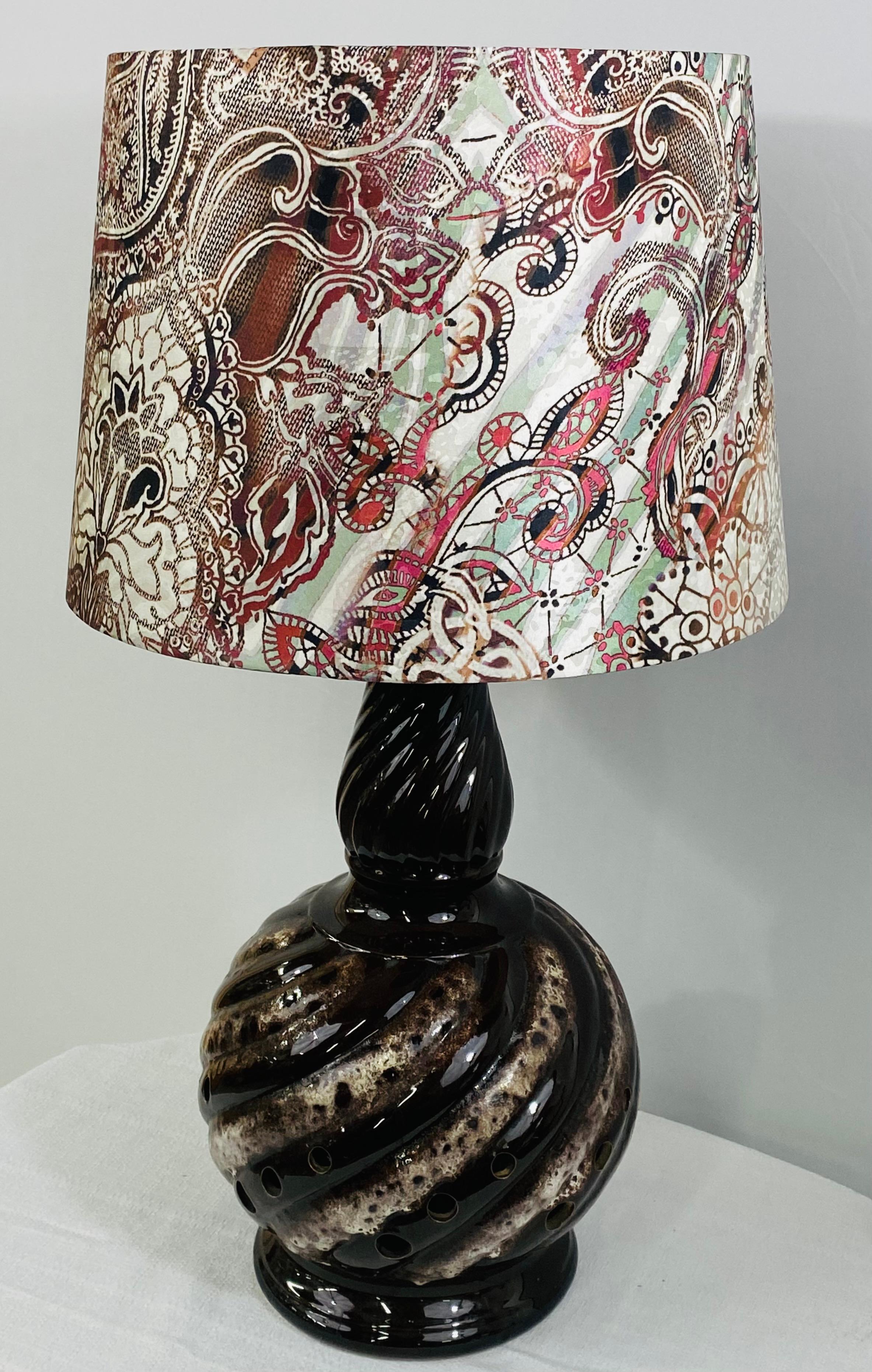 A stylish Boho Chic table lamp. The lamp is a vase or jar converted and has two lights installed , a standard bulbs as the main lighting source and a small light inside the jar. The lamp 's body is made of ceramic featuring wavy design in dark brown