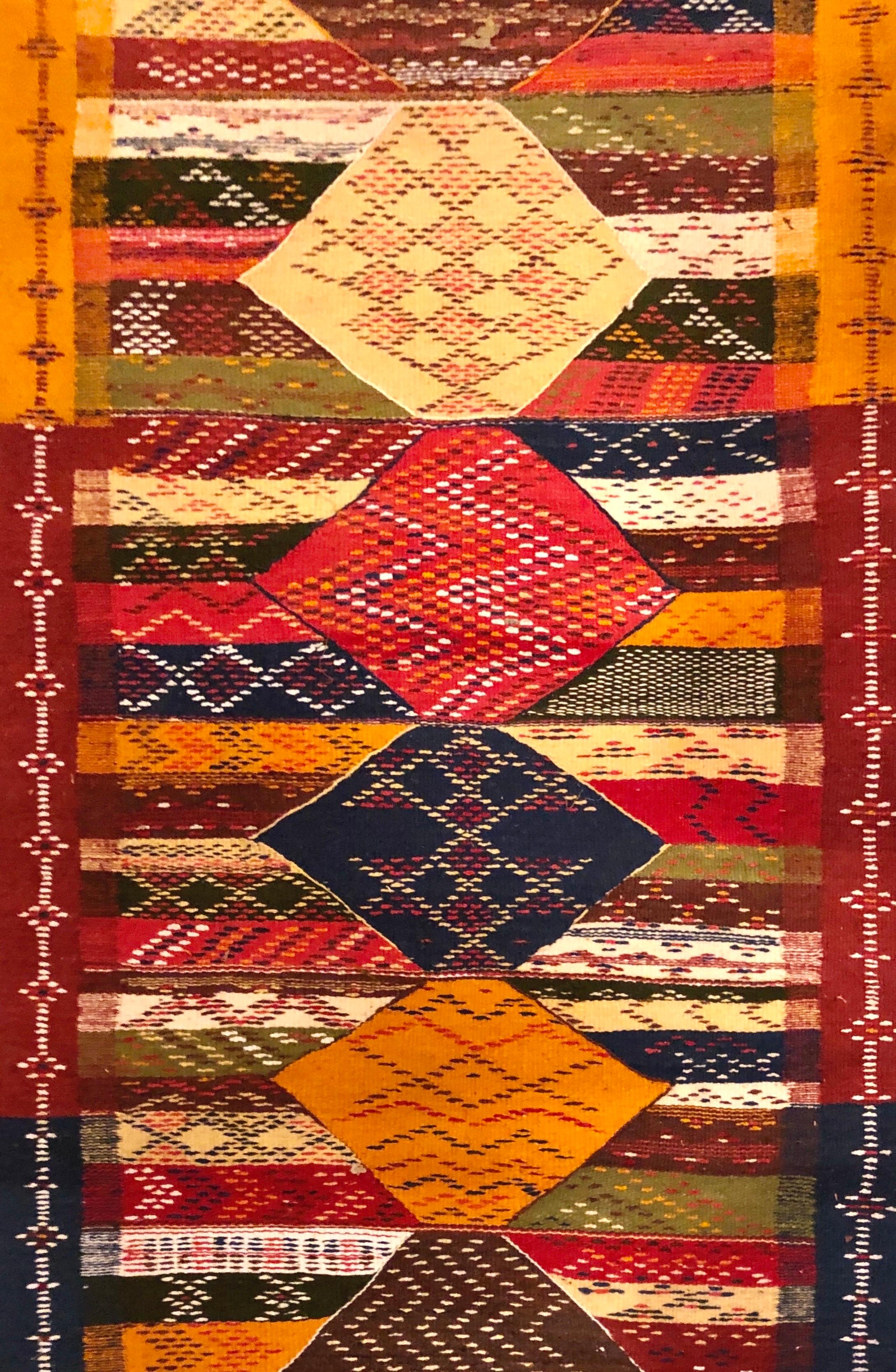 
Ein zeitloser marokkanischer Läufer im Boho-Chic mit rautenförmigen Mustern und tiefen Erdtönen. Der Läufer/Teppich, der eine atemberaubende Mischung aus Patchwork- und geometrischen Mustern zeigt, ist im Flachgewebe-Stil aus feinster, lokal