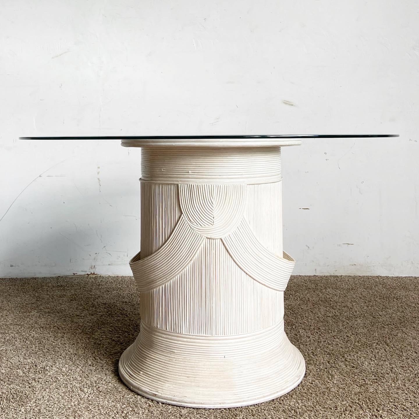 Elevate your dining experience with this Boho Chic Pencil Reed Pedestal Circular Glass Top Dining Table. Featuring an intricately crafted pencil reed base and a transparent glass top, this table is a unique blend of natural textures and modern