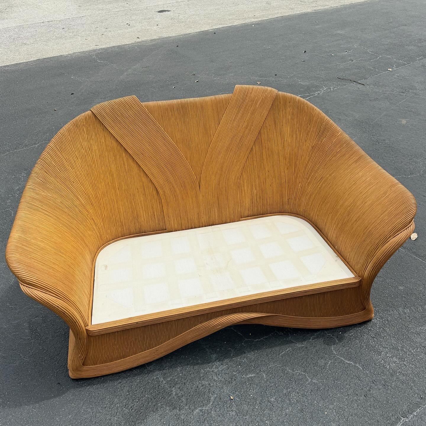 Embrace bohemian elegance with this charming Boho Chic Pencil Reed Love Seat Sofa. Featuring a unique ribbon design and intricate pencil reed construction, this vintage piece adds a touch of organic artistry to any space. The floral upholstery