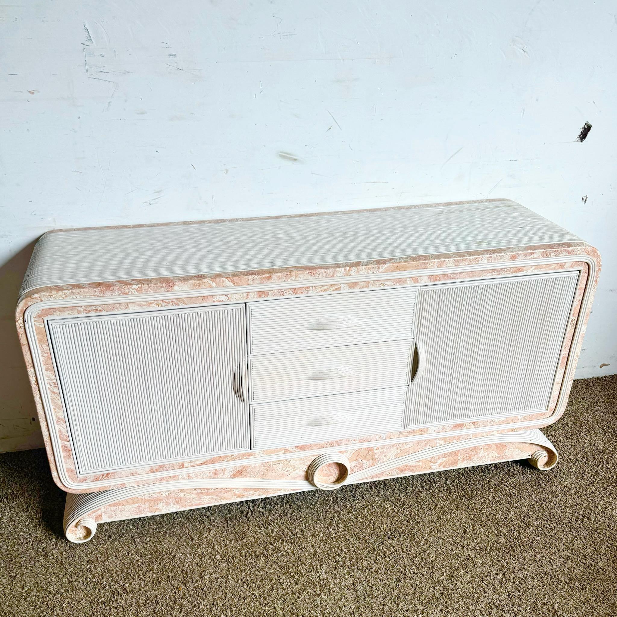 Eleva il tuo spazio con questa credenza Boho Chic in pietra tessellata rosa e nastro di canna da zucchero. Combinando il fascino senza tempo della pietra tessellata con intricati dettagli in canna, questo pezzo presenta una morbida tonalità rosa per