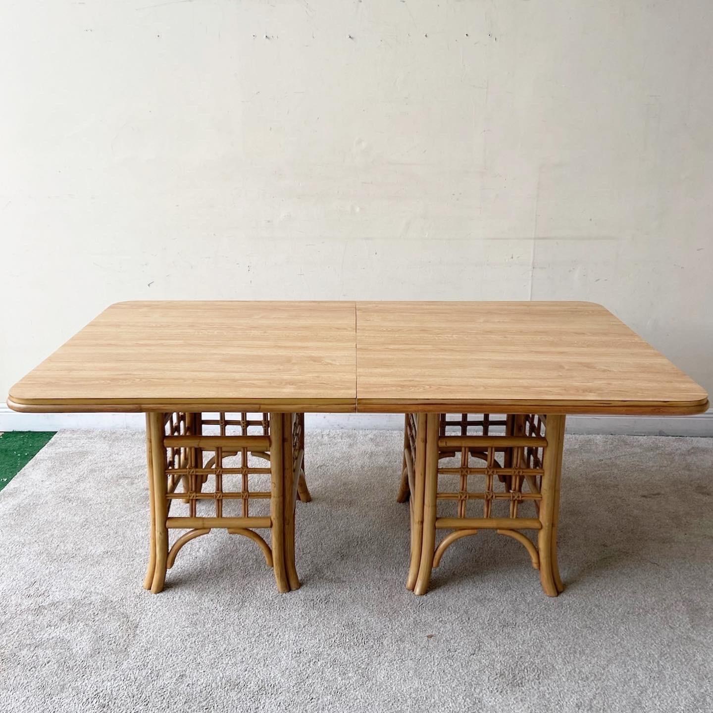 Exceptional vintage boho chic dining table. Features two bamboo rattan pedestals bases with a Woodgrain laminate top.
 