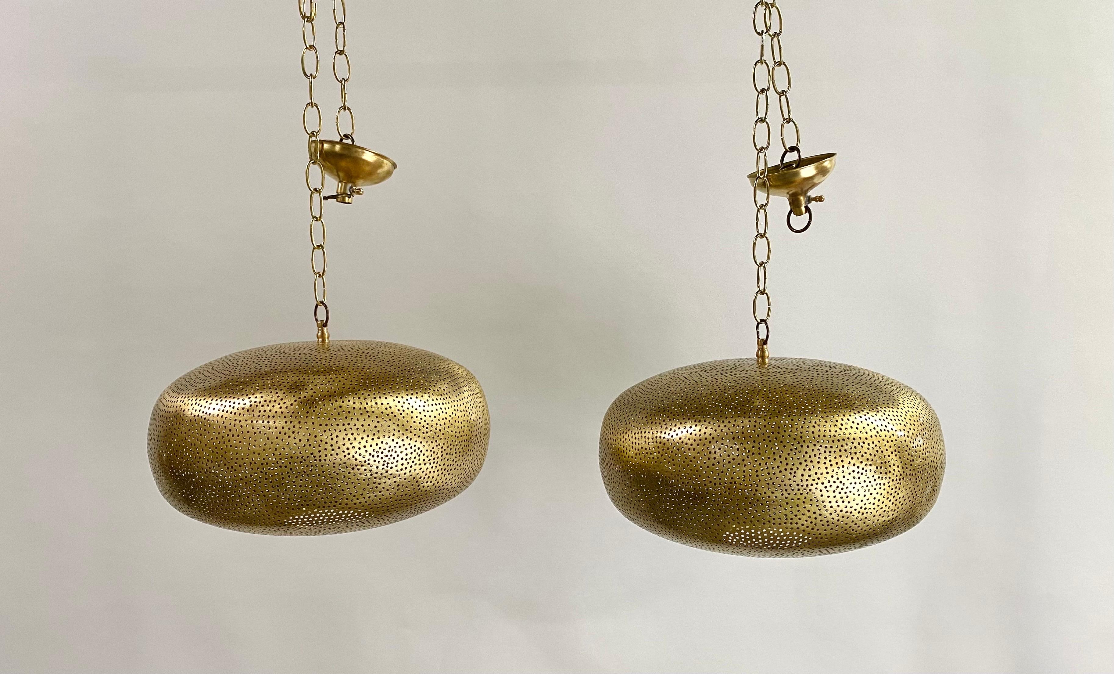 A pair of boho chic brass pendant or chandelier. These beautiful artisan-crafted pendants will add a note of exotic distinction to any room. Featuring hand-tooled brass and further enhanced with an oval retro shape, these pendants or lanterns