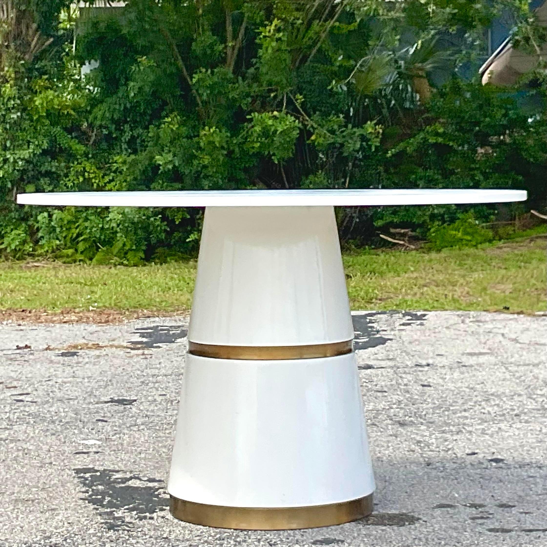 Vintage Boho center hall table. A chic and contemporary shape with a round top and tapered pedestal. White lacquered finish with repeating brass bands. Acquired from a Palm Beach estate. 