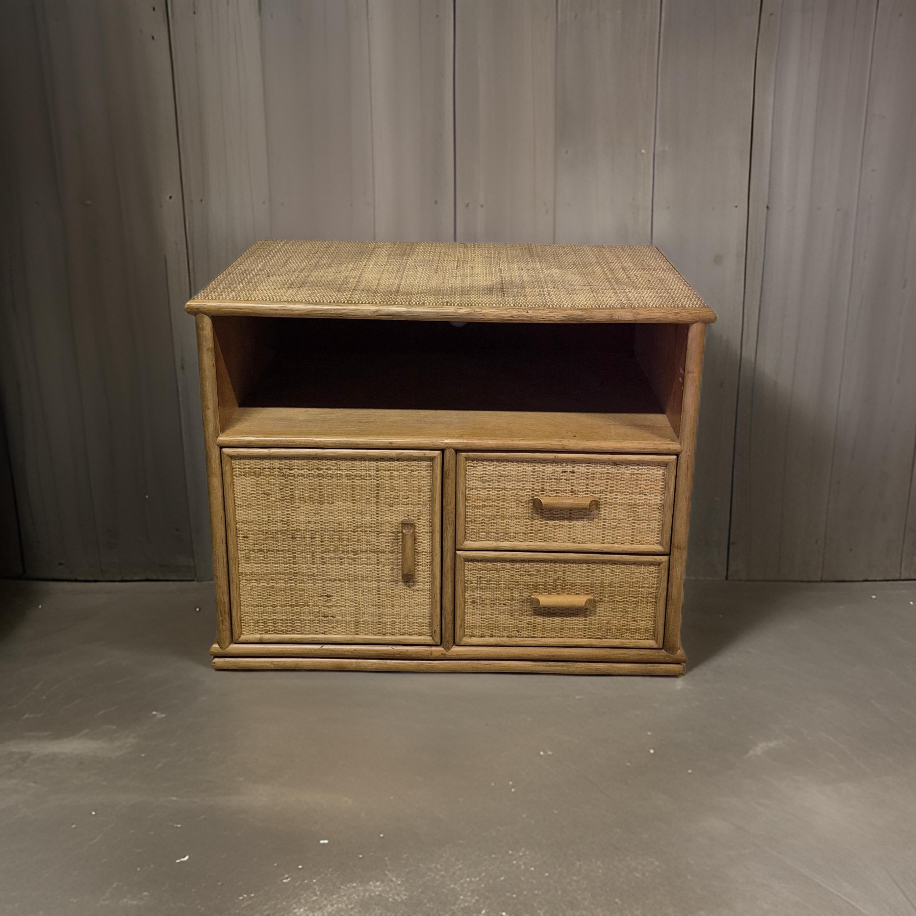 Piccola credenza in stile boemo. Ha un'anta, due cassetti e un vano portaoggetti aperto. Realizzato in legno e rivestito in rattan intrecciato. Il pannello posteriore presenta dei fori per far passare i cavi.

Nel complesso è in ottime condizioni,