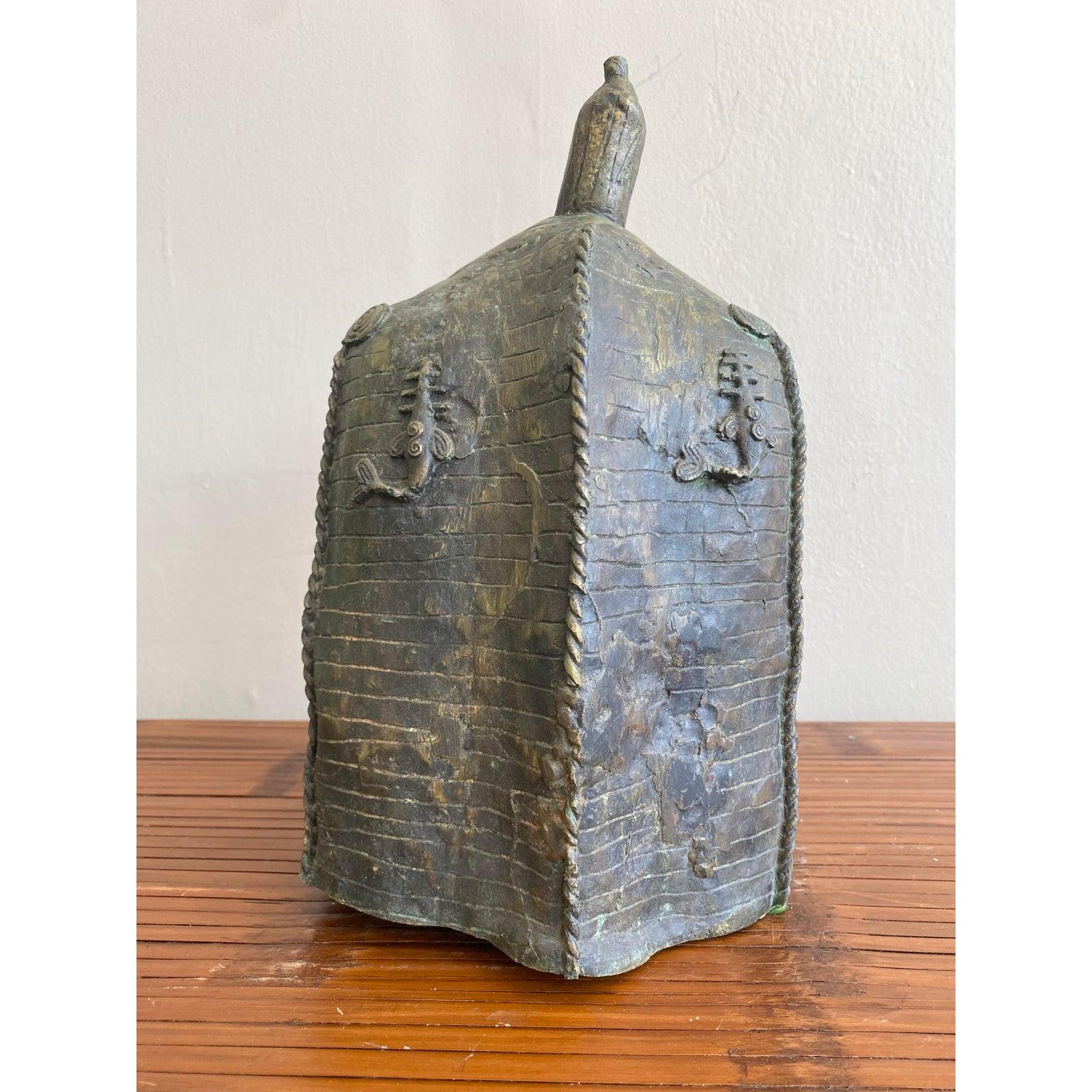 Dieses kraftvolle skulpturale Objekt verbindet zeremonielle Mystik mit brutalistischer Handwerkskunst. Das aus schwerem Metall gegossene Stück mit reichlich gesprenkelter Patina zeigt auf der Vorderseite ein kühnes, stilisiertes Gesicht mit