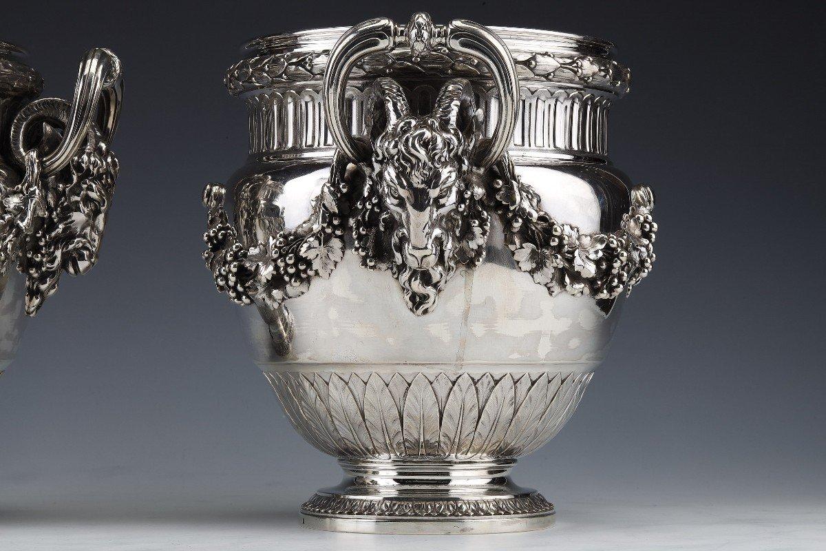 Pair of solid silver coolers mounted on a pedestal, engraved with a decoration of water leaves, halfway down a large garland of laurel leaves is connected to the handles represented by rams' heads surmounted by a grip in the shape of an ring. At the