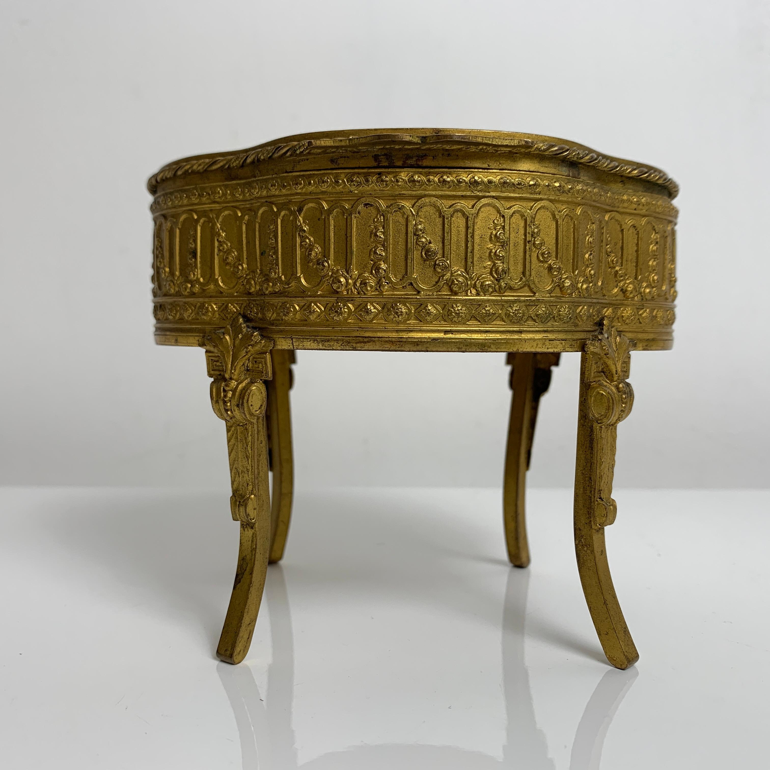Très élégant coffret a bijoux ancien en forme de mobilier miniature reposant sur 4 pieds. 

Construction ancienne, fin 19e dans le style Louis XVI. Sujet en bronze doré, rehaussé d'un portrait de femme en médaillon. L'intérieur du coffret de forme