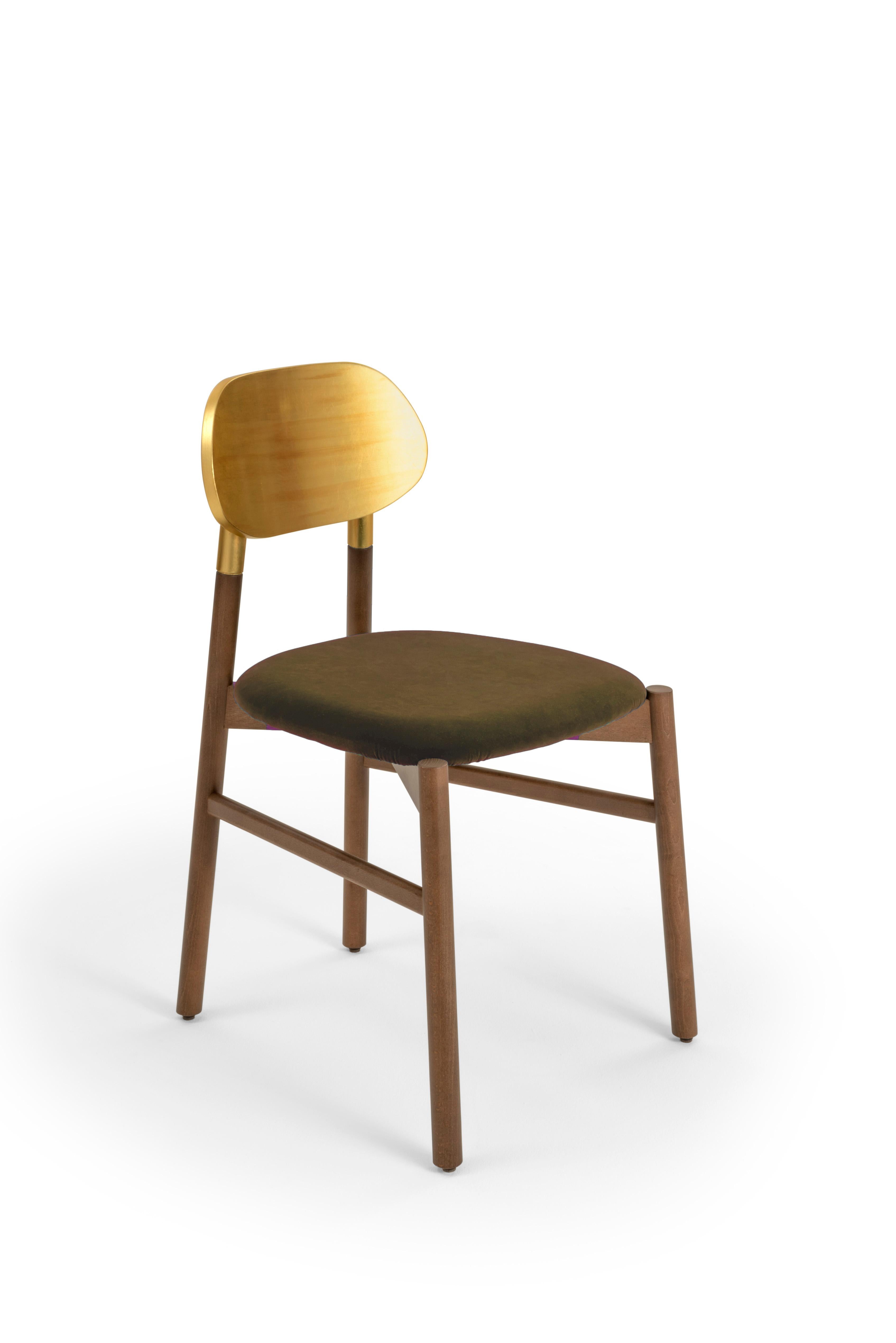Chaise tapissée Bokken en bois de hêtre teinté noyer, dossier en feuille d'or et assise rembourrée recouverte d'un velours Rubelli de qualité supérieure. Qualité italienne pure.
Une chaise essentielle dans la forme, mais précieuse dans les