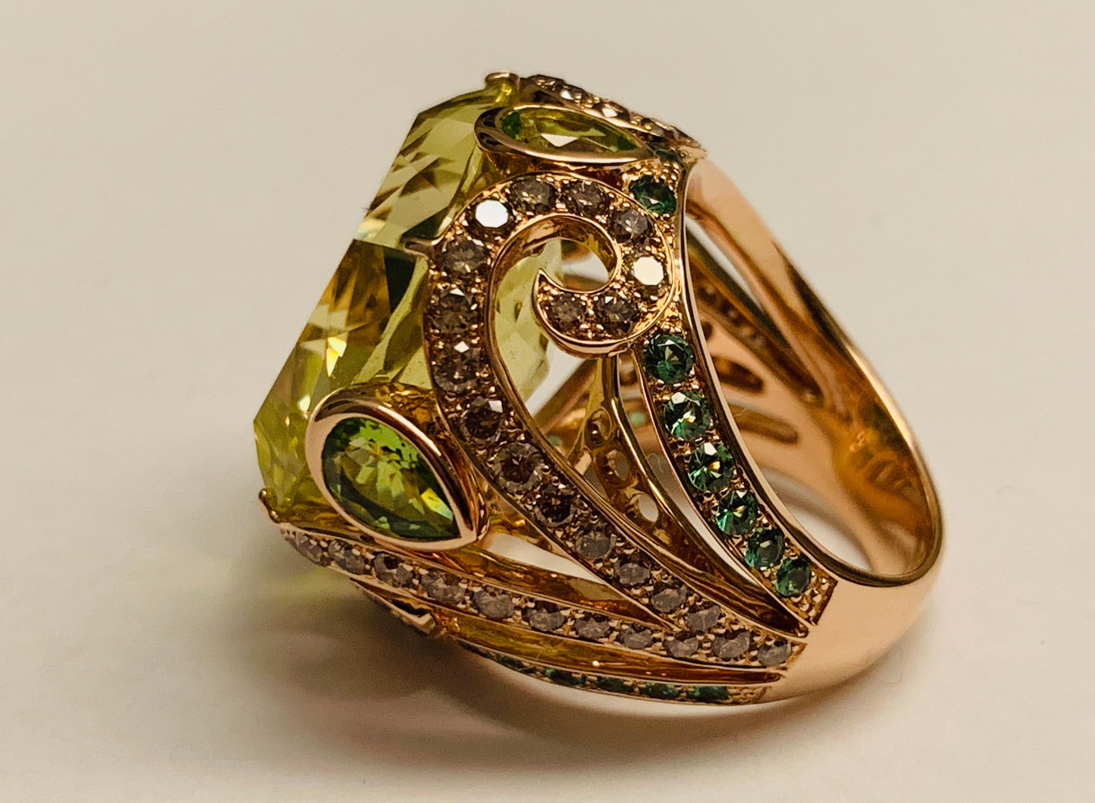This statement Cocktail Ring centering a large cushion shaped vivid yellowish green lemon citrine. Surrounded by Champagne colored glittering diamonds and Tsavorite garnets, all fancifully set in 18 K Rosegold.
The ring is currently size 54/14 but