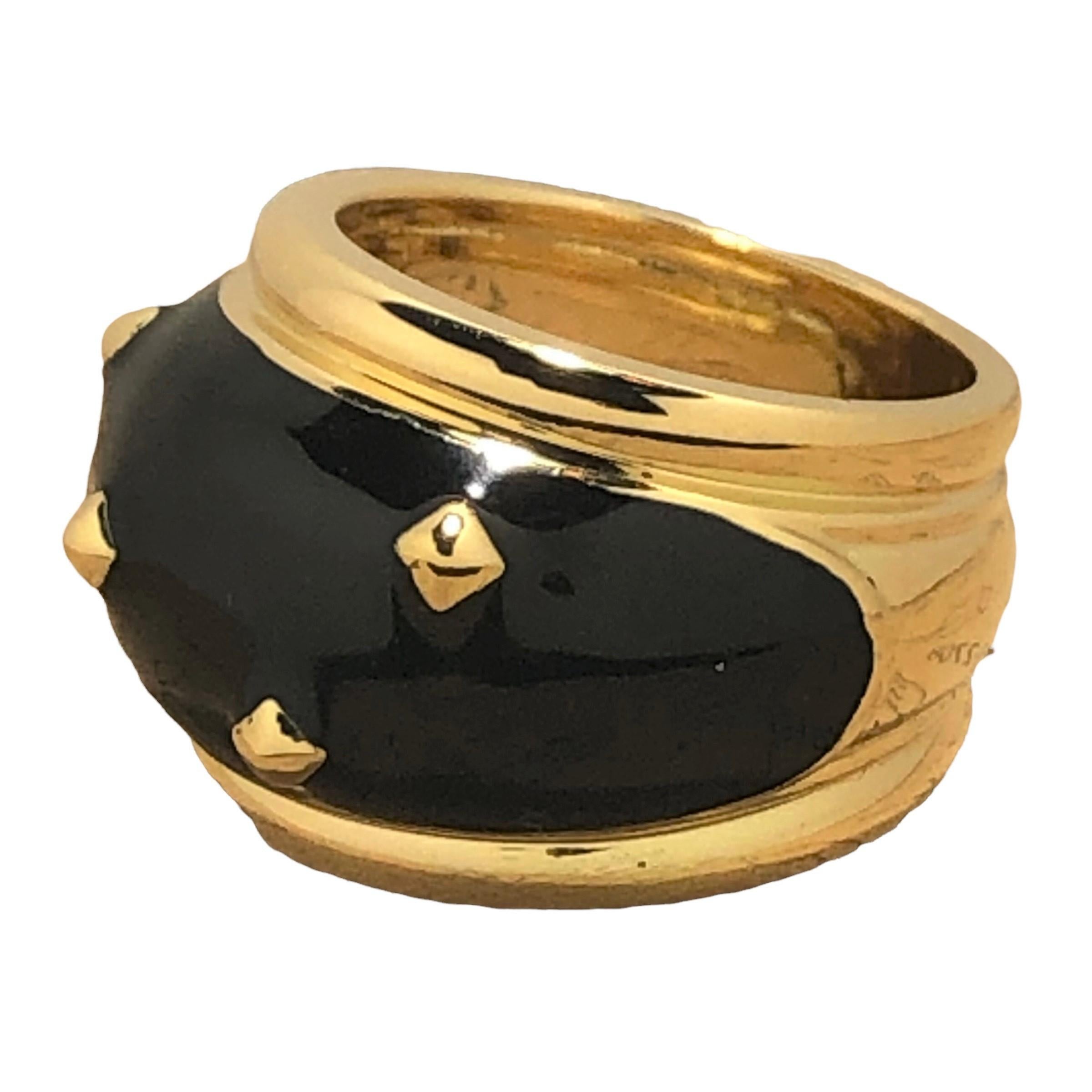 This interesting 18k yellow gold, late-20th century bombe dome ring features a field of glossy black enamel which is punctuated at regular intervals by pyramidal gold studs. The entire design area is flanked  with a half round gold border which