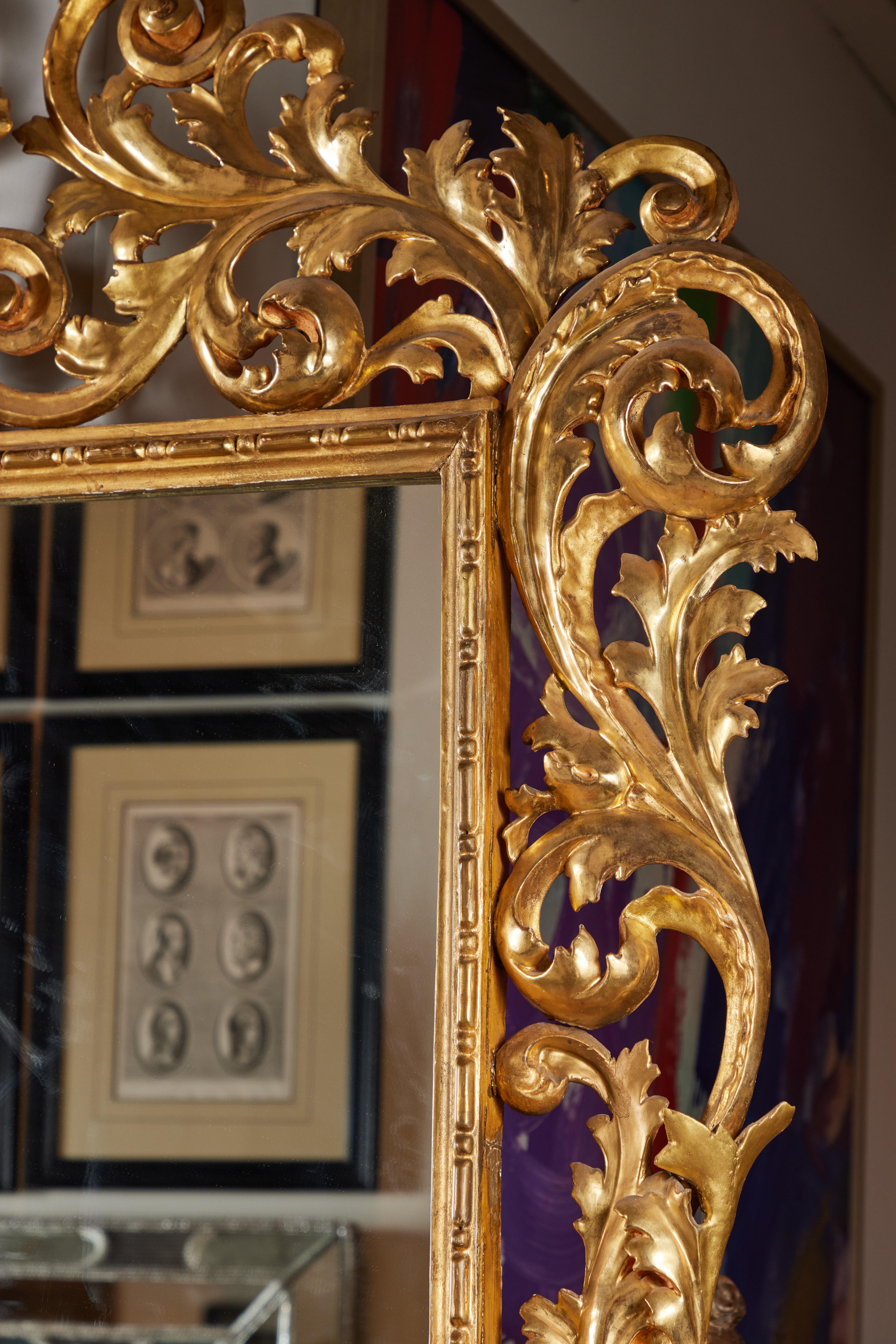 Cadre florentin de grande taille, sculpté à la main et doré à l'or fin 22 carats, inséré dans un verre plus récent. Le cadre dramatique, de forme serpentine et feuillue, s'élève vers une belle couronne centrée sur une urne sculptée en relief et