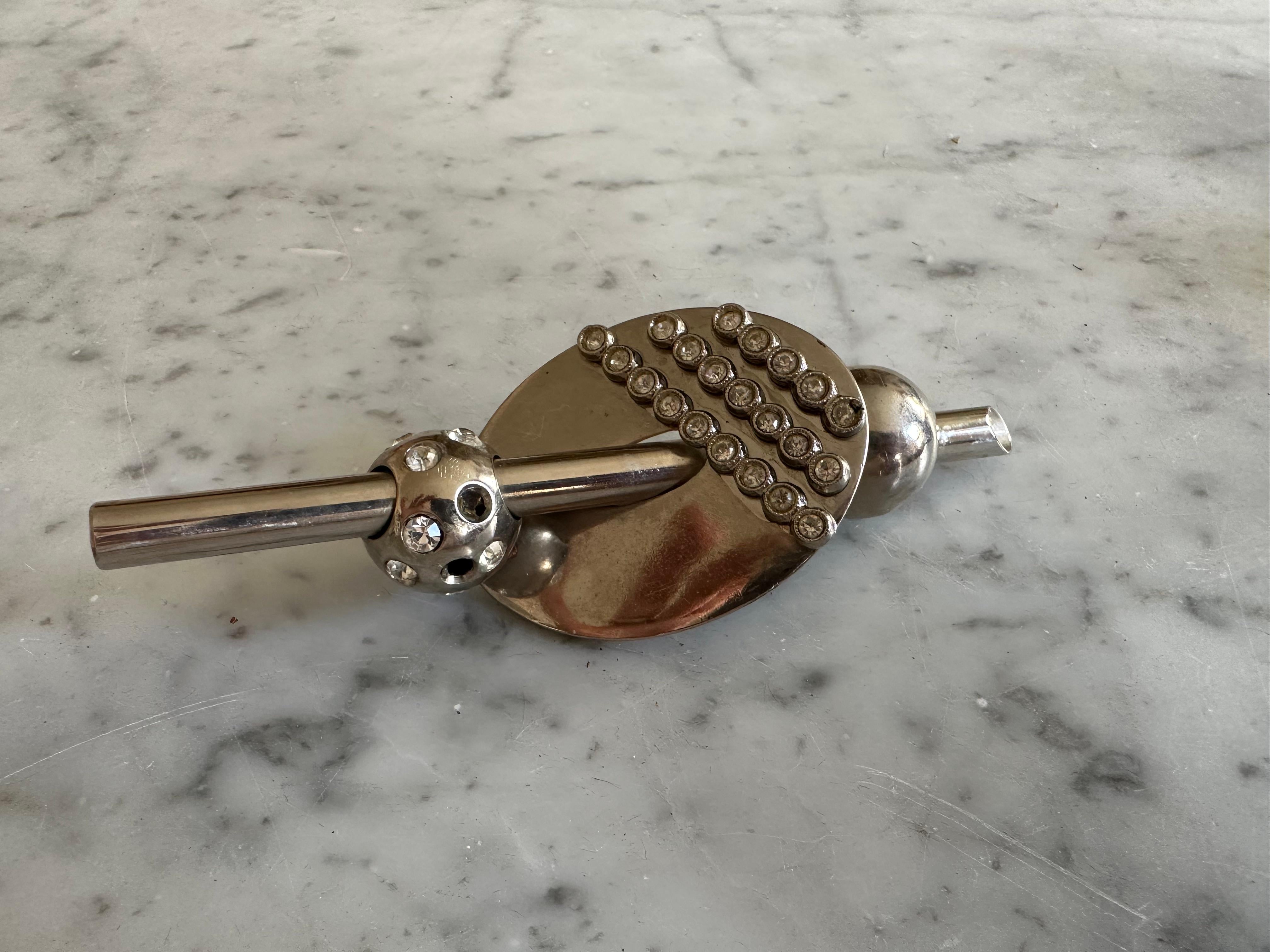 This striking vintage brooch by Gianni Versace is a true collector’s item and a bold example of 1980s costume jewelry. Designed in a large, extroverted style typical of the era, this piece is made of silver-toned metal and set with sparkling glass