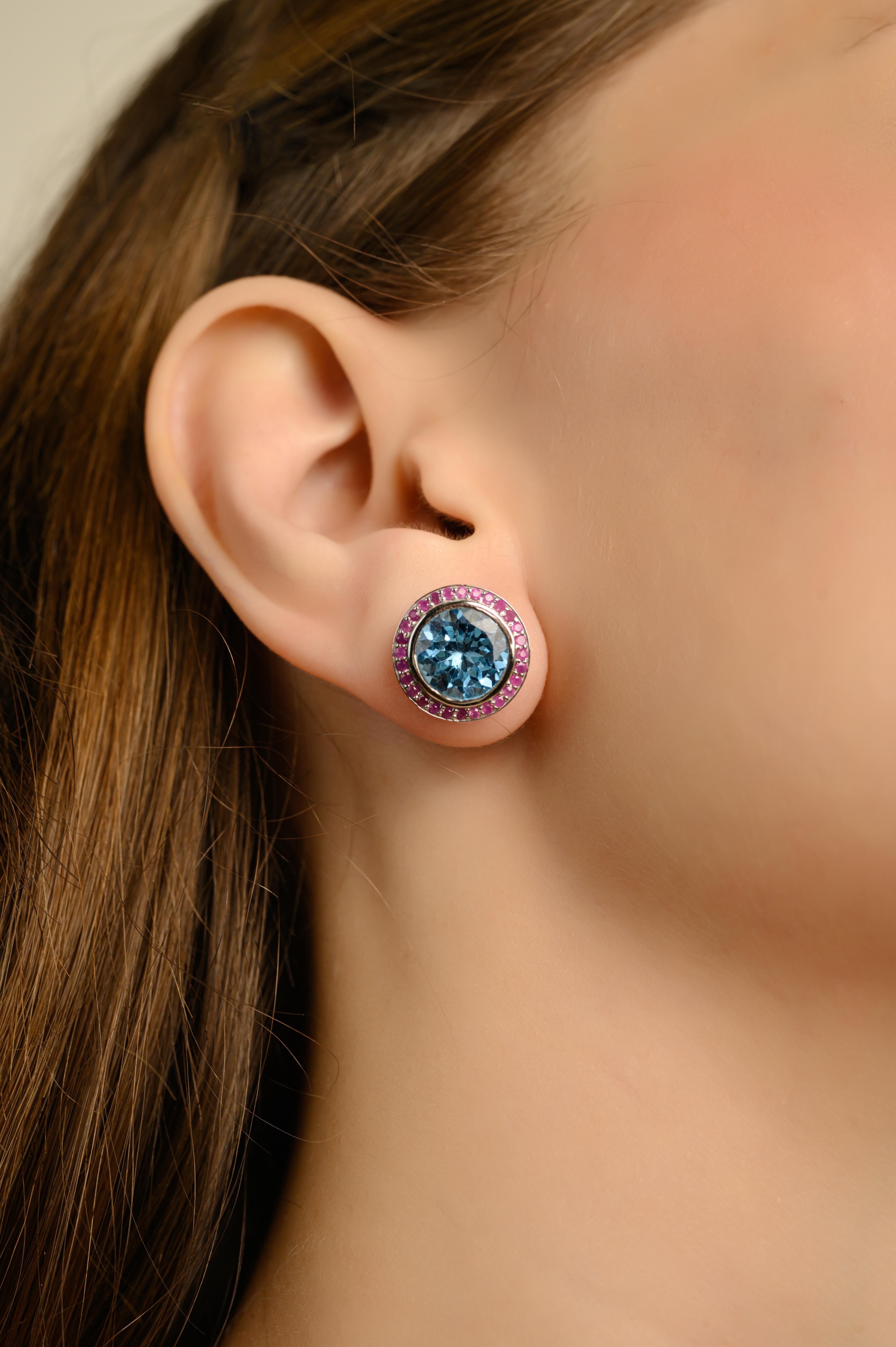 Questi audaci orecchini a cerchio in Topazio Blu e Rubino sono orecchini a cerchio vibranti, realizzati a mano in pregiato argento sterling 925. Al centro di ogni orecchino si trova un topazio blu brillante a taglio rotondo, incastonato in un