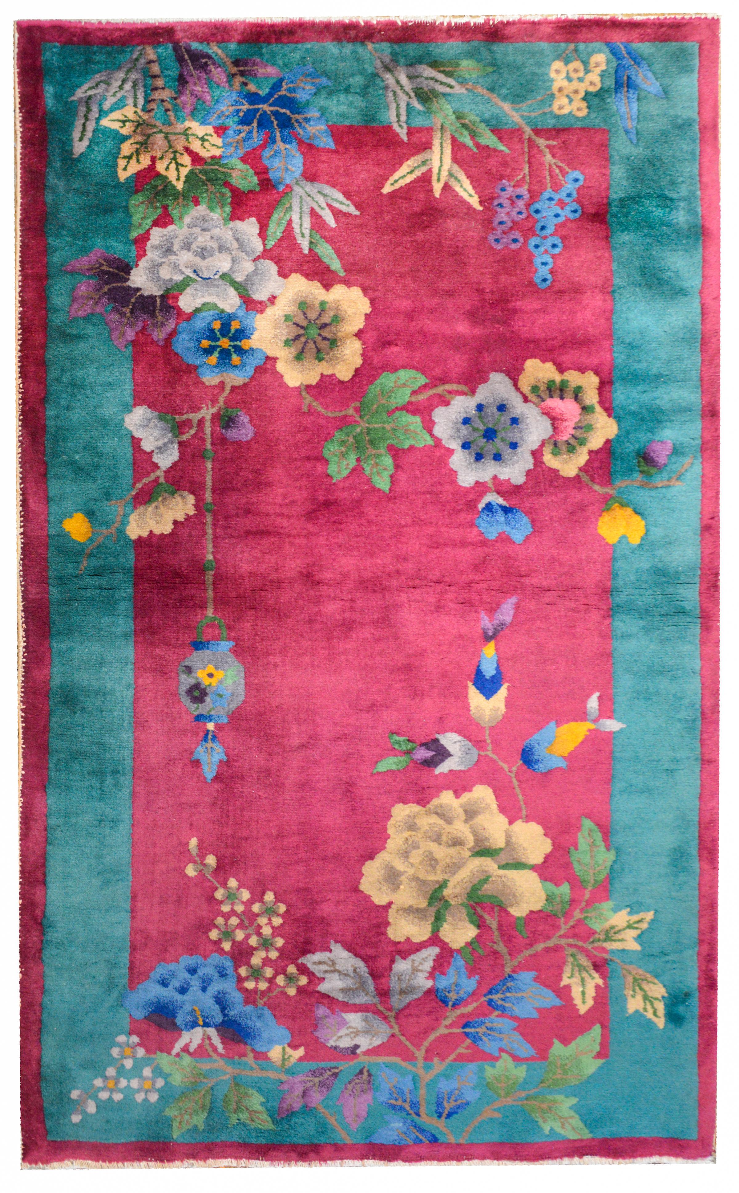 A bold and beautiful early 20th century Chinese Art Deco rug with a cranberry colored field surrounded by a wide turquoise stripe border. Several multi-colored peonies are overlaid in an asymmetrical composition.