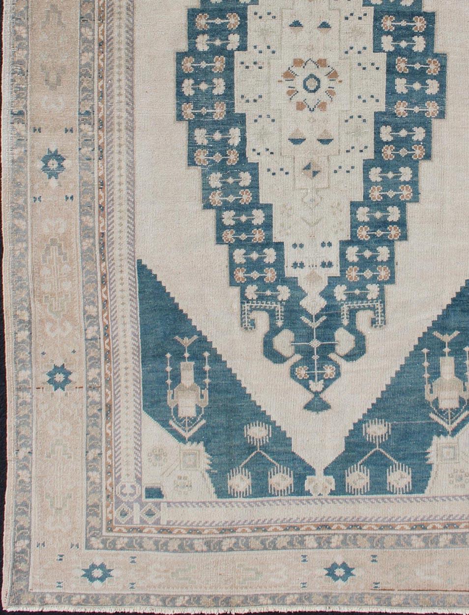Medallion design Oushak rug from Turkey in cream and blue tones, rug TU-ALK-4895, country of origin / type: Turkey / Oushak, circa 1940

This vintage Turkish Oushak rug features a unique medallion design. The multi-banded border frames the designs