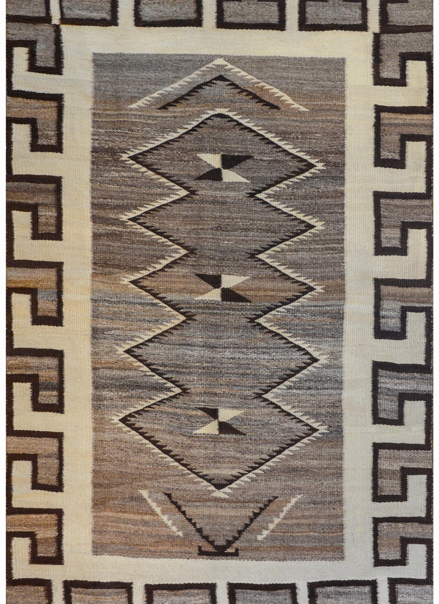 A bold early 20th century Navajo rug with a wonderful large-scale white meandering motif surrounding an abrash gray field with a large zigzag patterned motif.