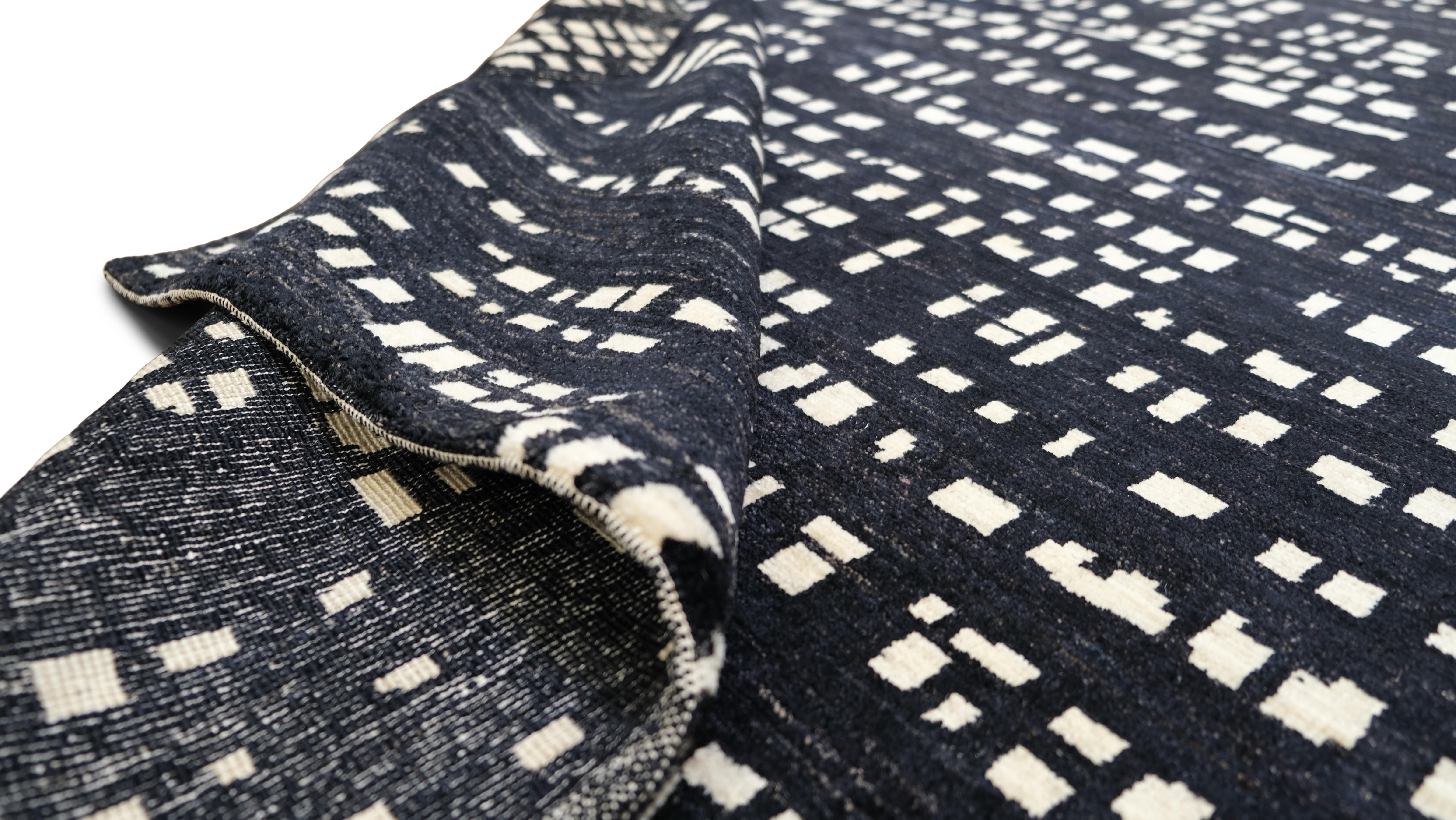 Elevate your interior with this striking hand-knotted wool rug, featuring a bold geometric pattern. The contemporary abstract design showcases an interplay of irregular grid-like shapes, creating a visual rhythm that adds character and depth to any