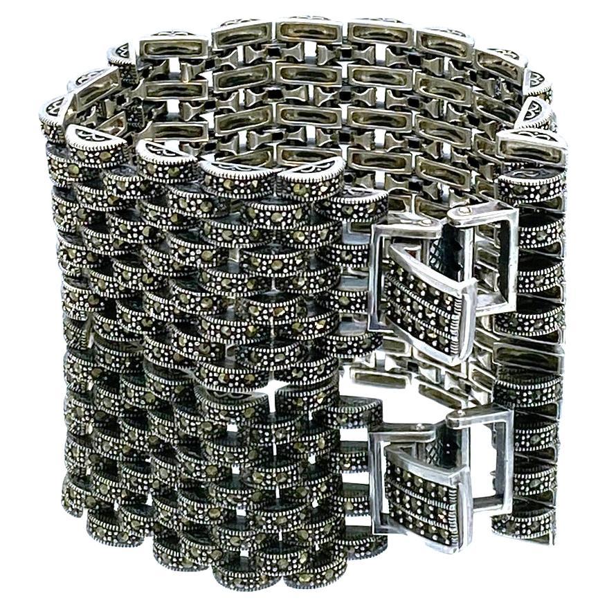 Il s'agit d'un bracelet à maillons en marcassite de style Art déco. Ce bracelet de plus de 77 grammes comporte neuf rangées de petits segments incrustés de marcassite, reliés entre eux par un fermoir à boucle déployante. Il pouvait être porté par un