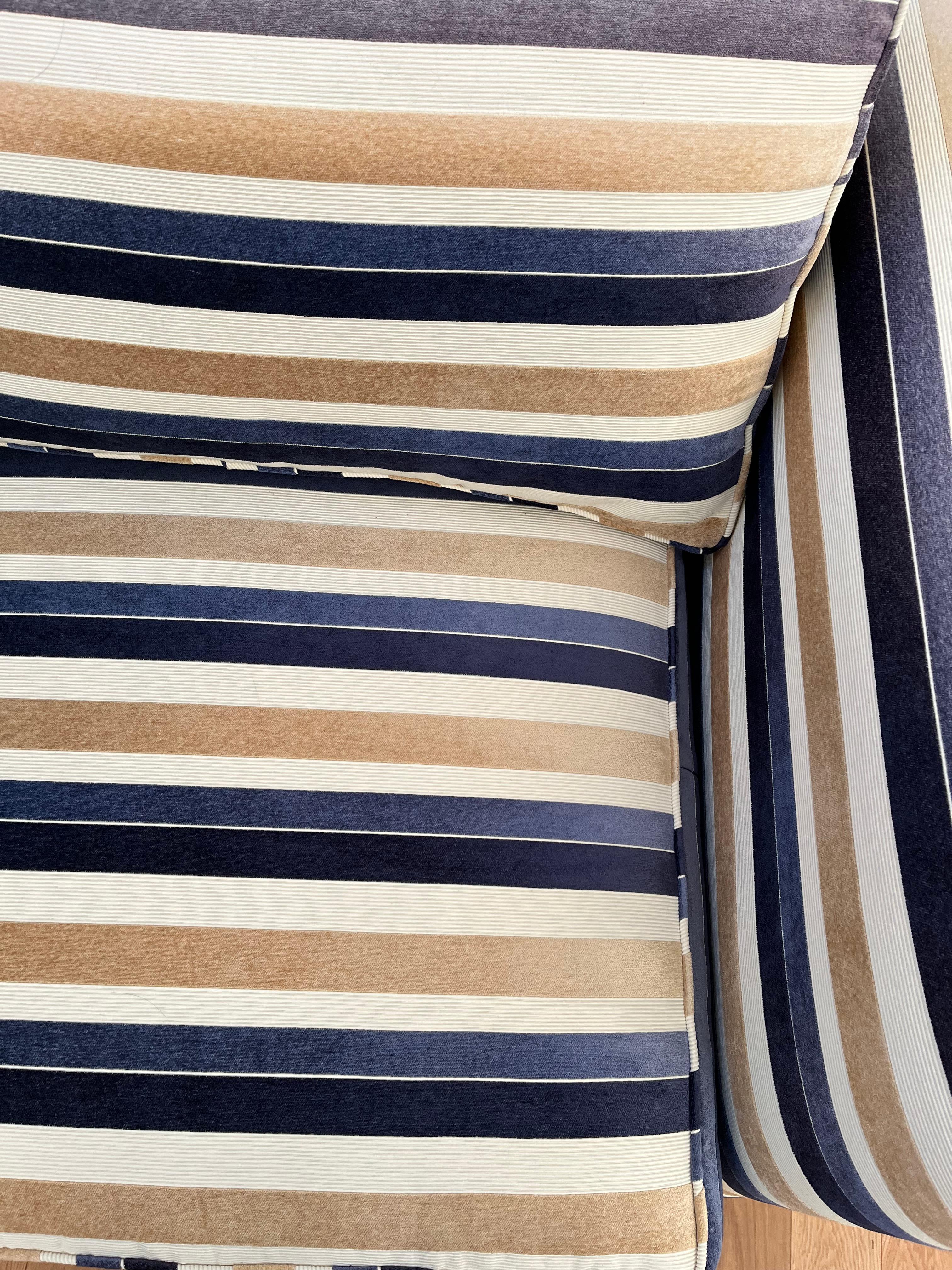 Un très beau canapé à rayures audacieuses en tissu velours or, bleu et crème.