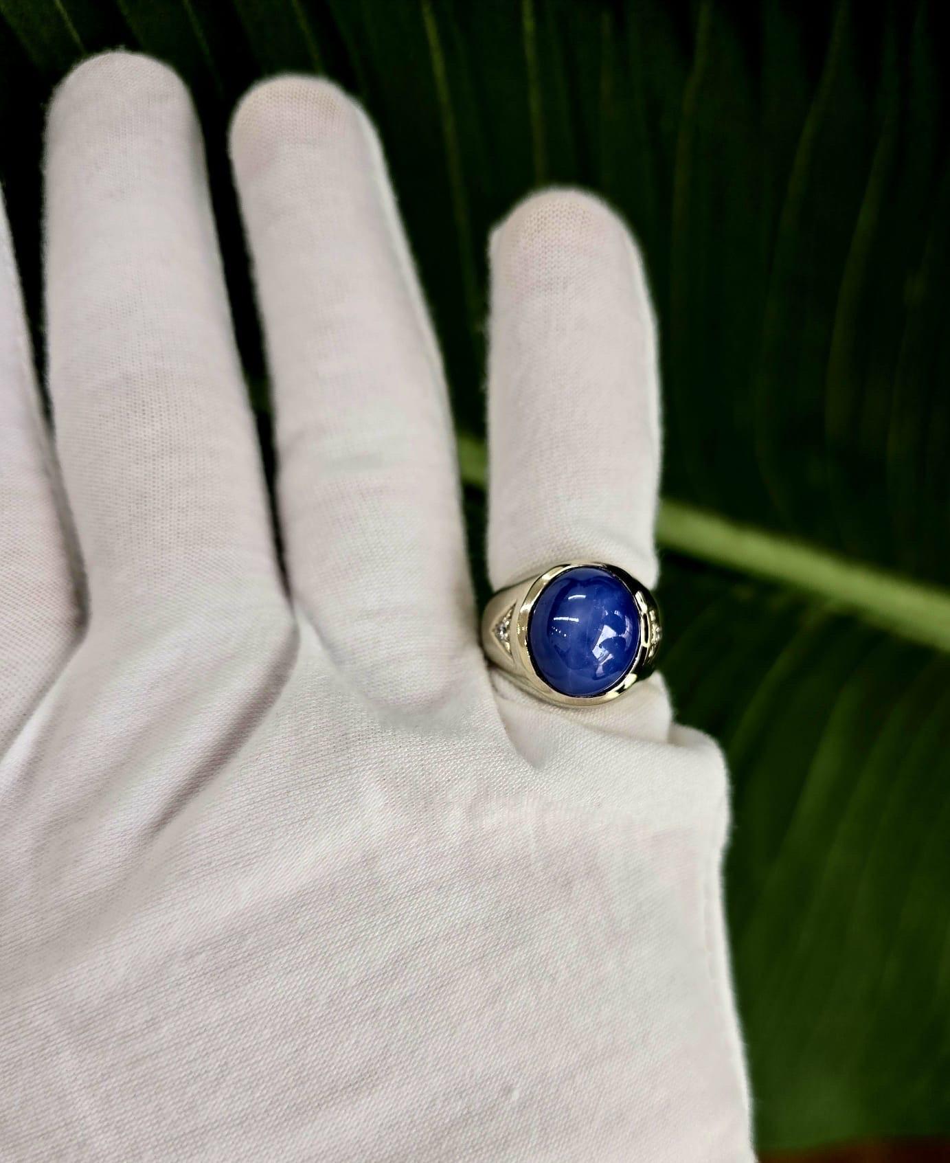 Une bague vintage pour homme de taille 7.75 mettant en valeur un saphir étoilé bleu vif certifié par le GIA pesant environ 17.77 grammes (brut), serti dans un chaton en or blanc poli. La pierre centrale ovale taillée en cabochon mesure 14,37 x 12,19