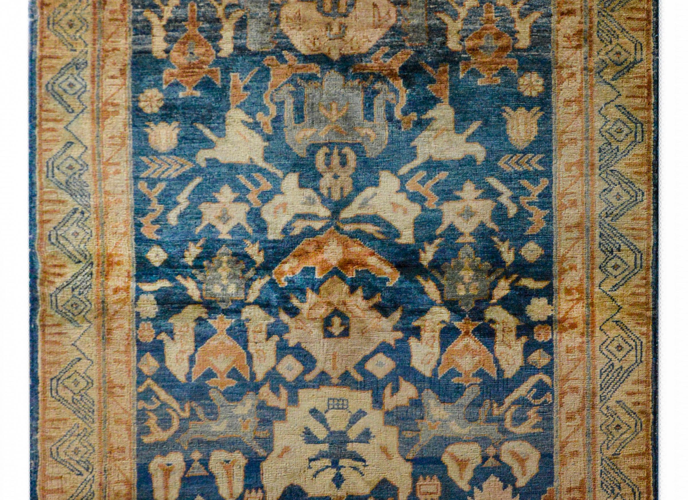 A fantastic bold vintage Anatolian Turkish rug with a strong tribal pattern woven in muted oranges, blues, creams, and reds, all set against a dark indigo background. The border is beautiful with a stylized floral pattern woven with thin linework.