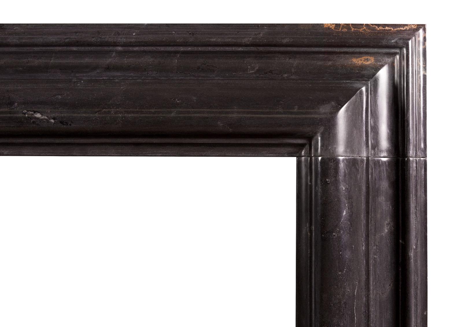 An English moulded bolection fireplace in black marble. Based on a period original. An elegant shape. Modern. Please note that whilst the marble is largely pure black in color there is a small area of golden veining to the top right hand corner of