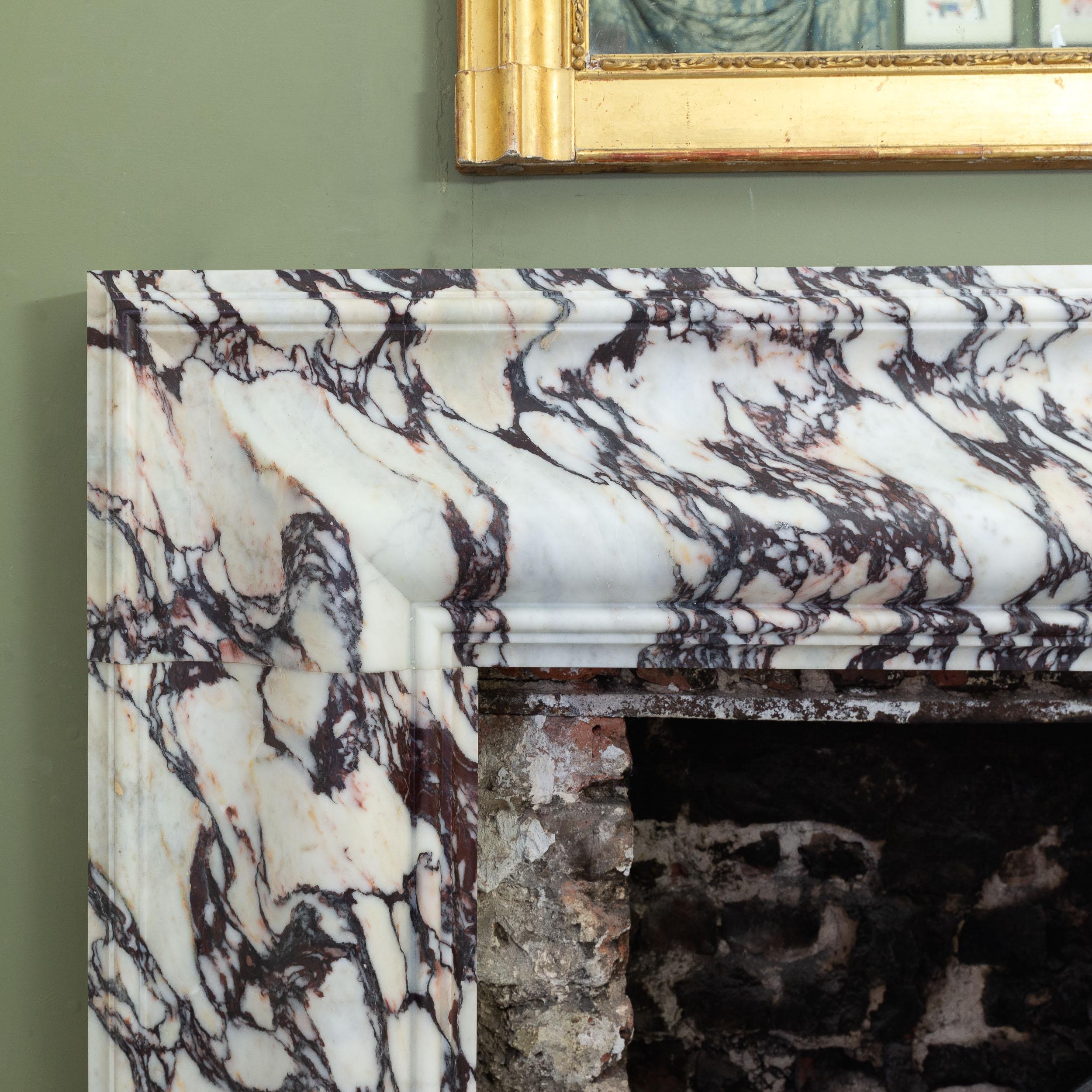 A striking bolection fireplace in Italian Breccia Viola marble, modern and in the Queen Anne style, recently salvaged from a property in Mayfair, the ogee mould frame on canted block feet. 

129.5cm (51