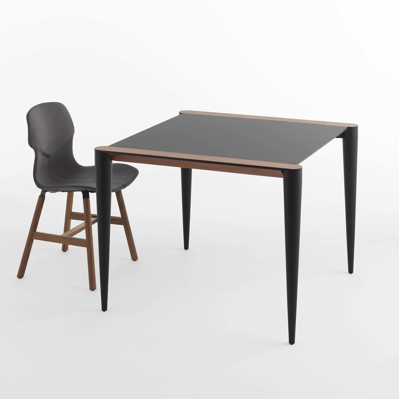 Resting on black-lacquered aluminum conical legs, this bistrot table is characterized by a distinctive top made of Fenix, a new material created with nanotechnology that renders the surface anti-fingerprint, resistant to scratch and suitable for