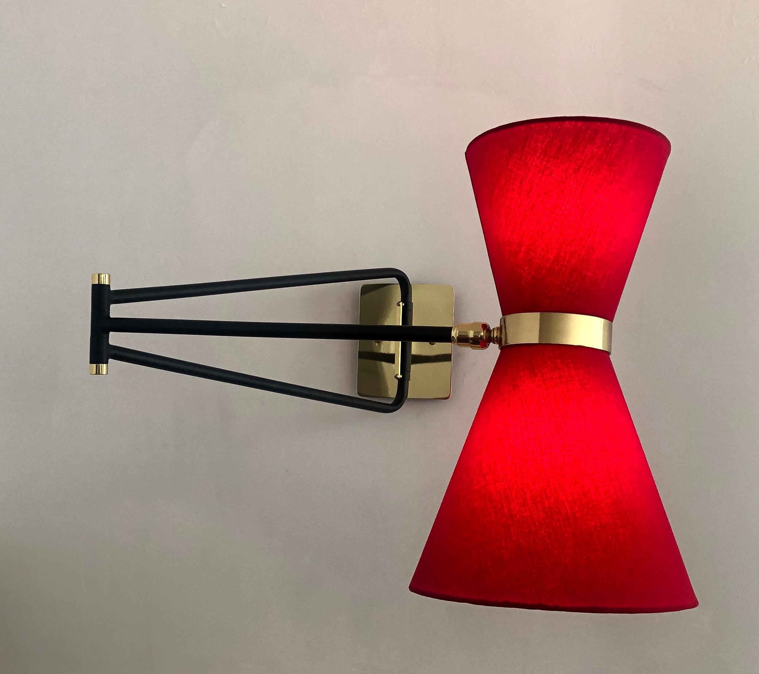 This sleek sconce is 1950s French midcentury by inspiration. The light with it double shade and articulated arm creates a versatile lighting source. The head pivots to direct the light of the two candelabra based bulbs in various direction while the