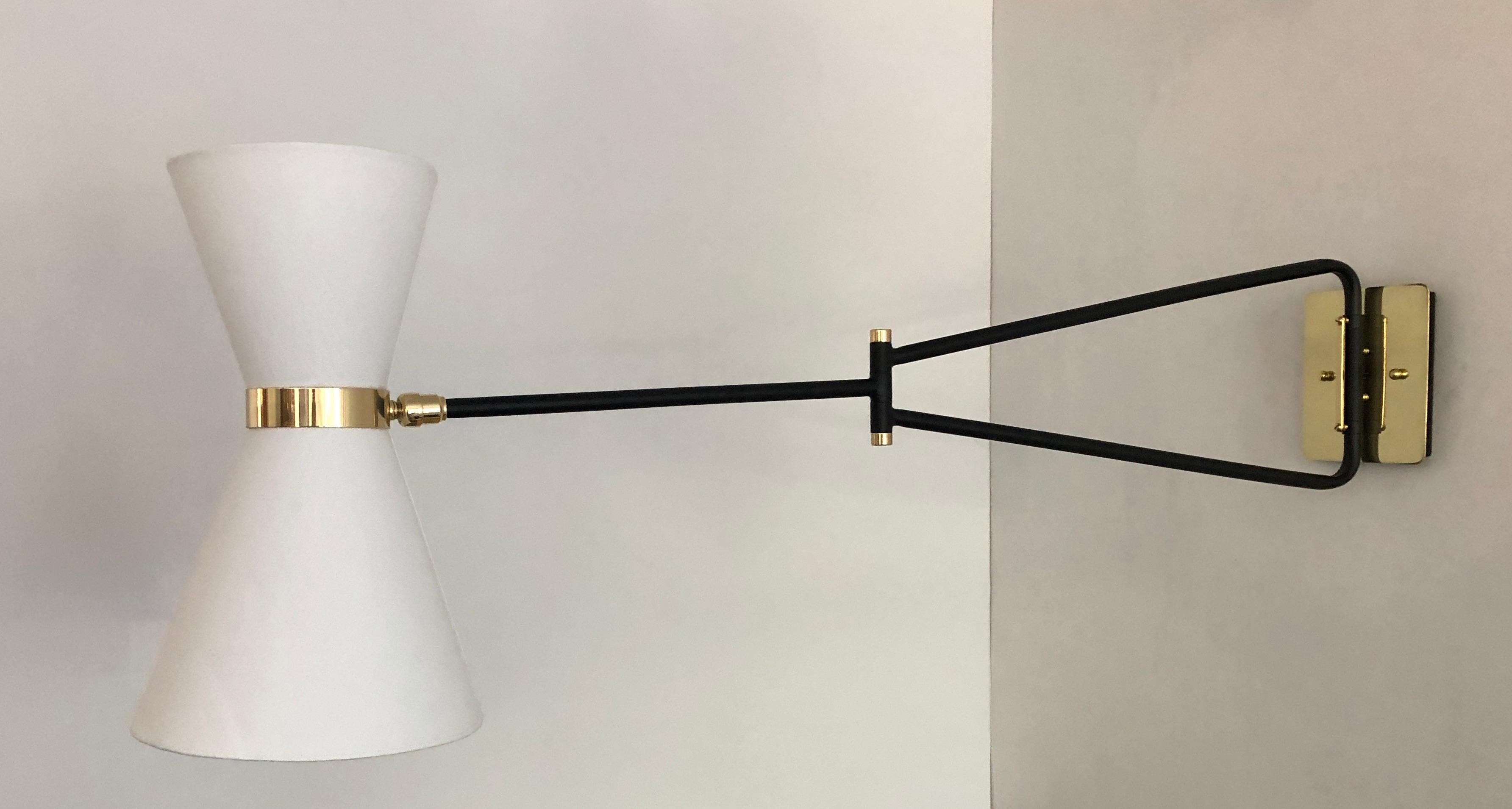 This sleek sconce is 1950s French midcentury by inspiration. The light with it double shade and articulated arm creates a versatile lighting source. The head pivots to direct the light of the two candelabra based bulbs in various direction while the