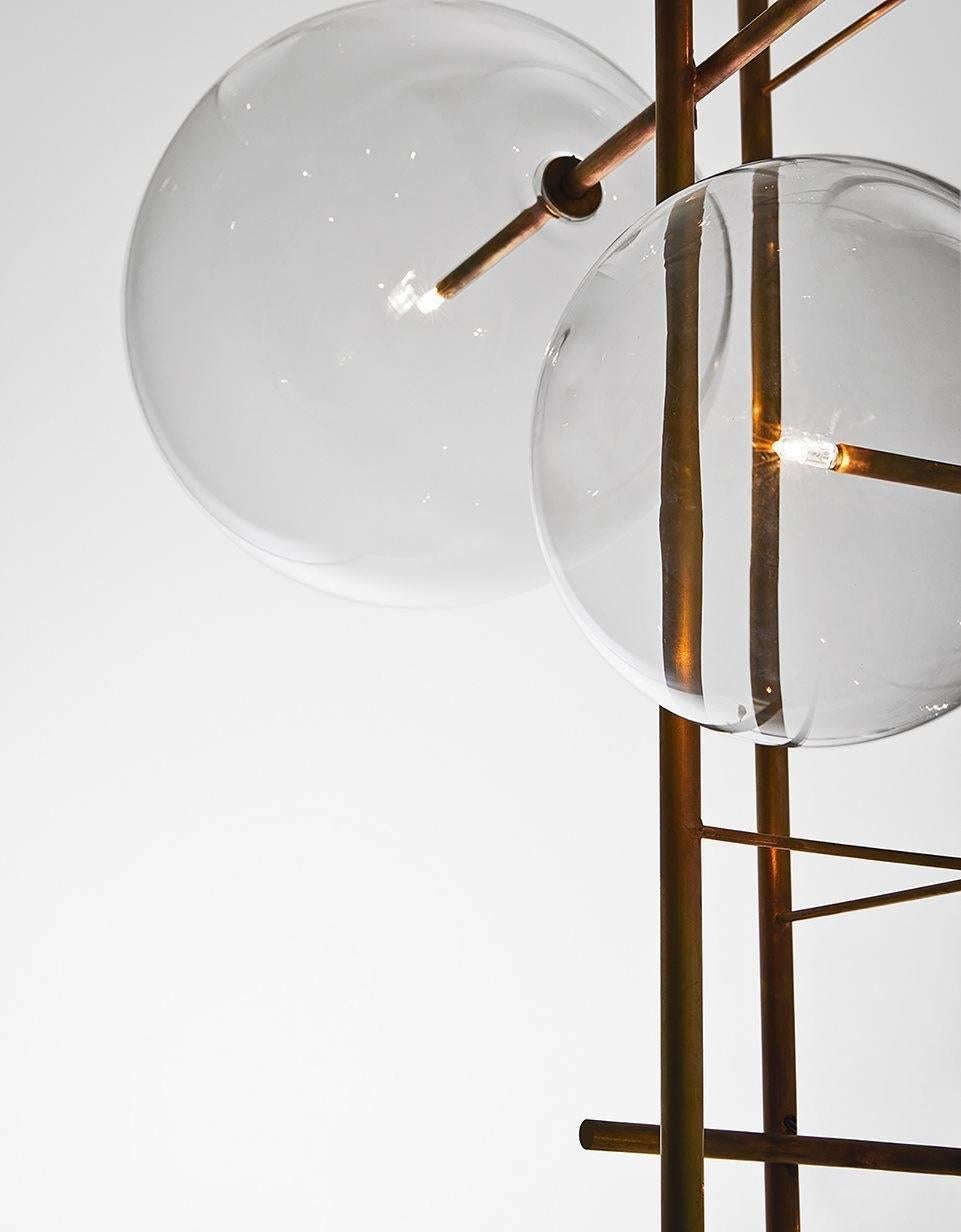 Bolle Tela is a suspension light fixture with a linear composition of eight blown glass globes held together with a hand burnished brass structure. Bolle Tela was designed to hang individually or to be hung in a cluster of fixtures to create the
