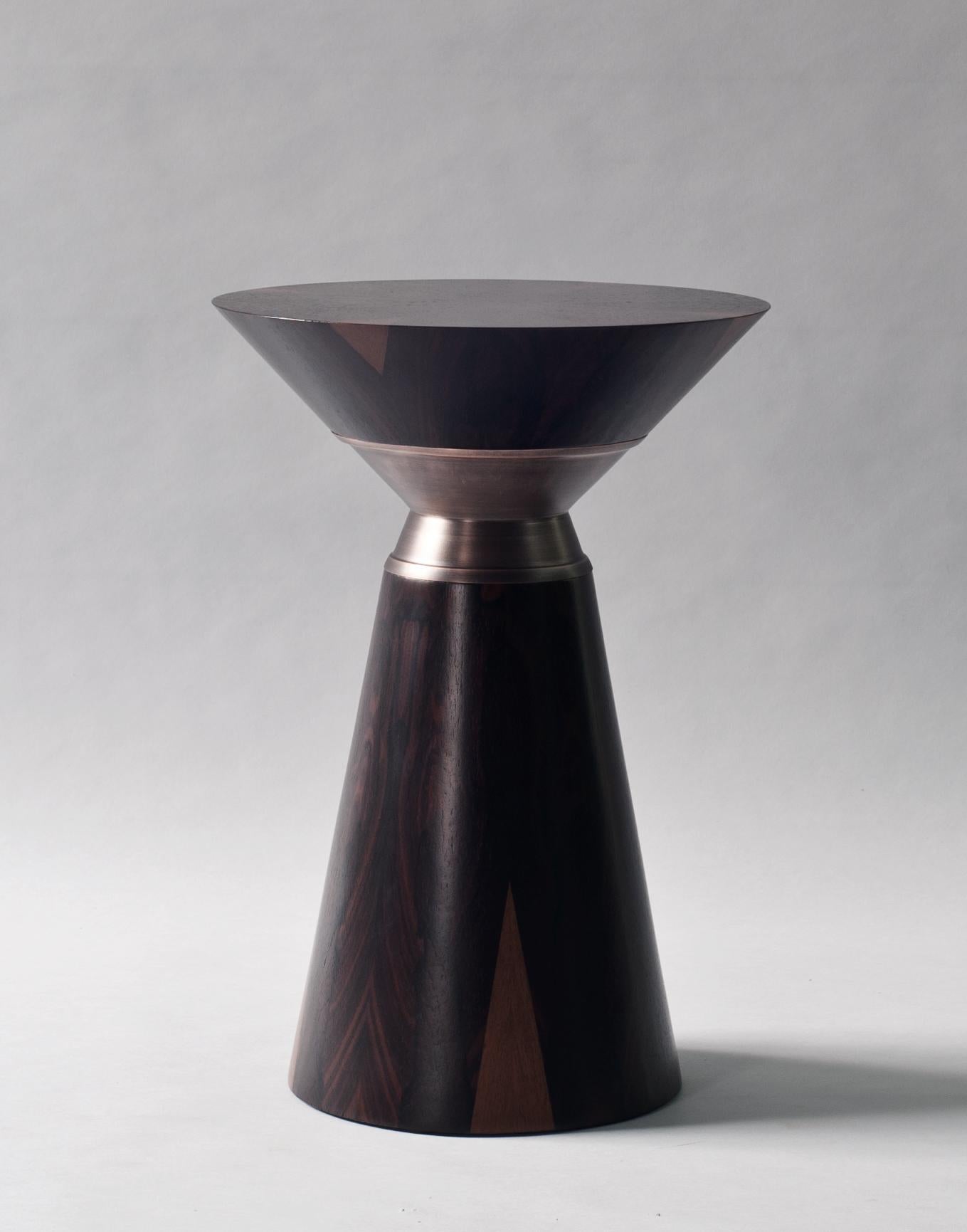 Bolo side table by DeMuro Das.
Dimensions: 35 x H 50 cm
Materials: Ziricote - Matte 
 Solid bronze - Satin 
Dimensions and finishes can be customized.

DeMuro Das is an international design firm and the aesthetic and cultural coalescence of