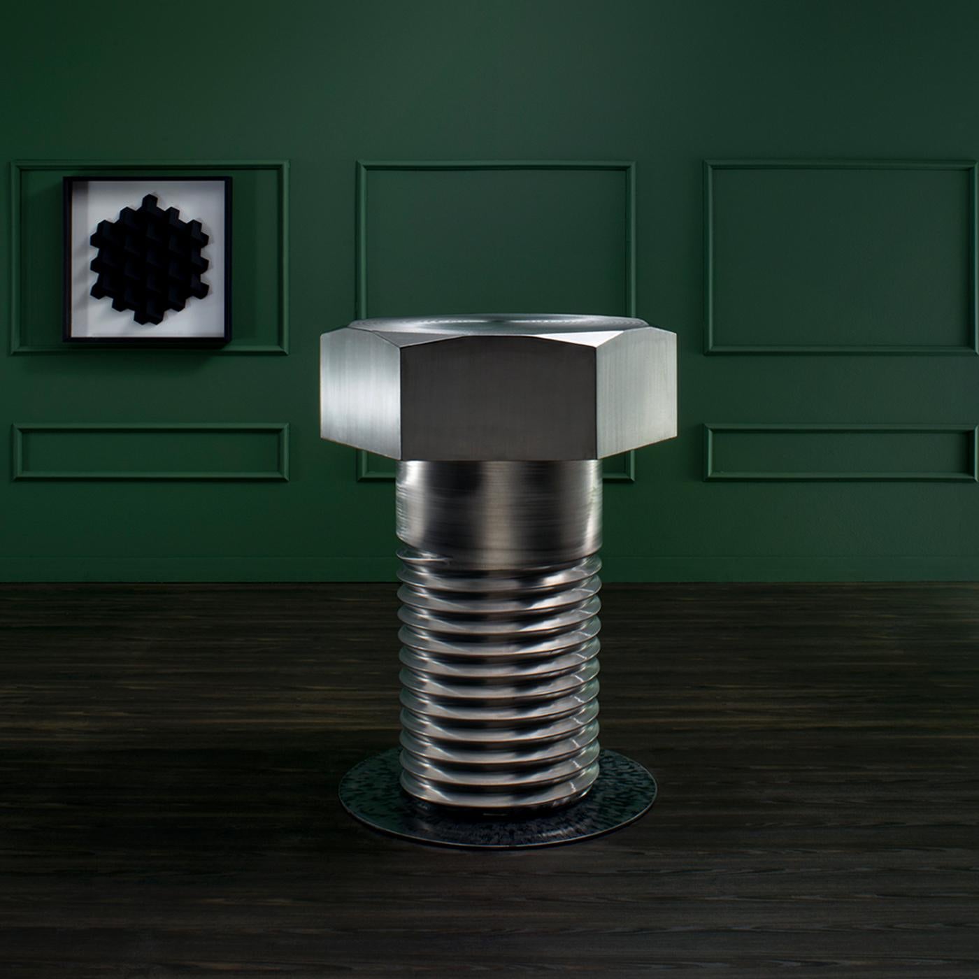Functioning as a side table or as an element of interior decoration, this handcrafted table boasts an ingenious design. Shaped like a big, solid bolt, it is entirely made of stainless steel, and it can be completed with a set of bolt-inspired