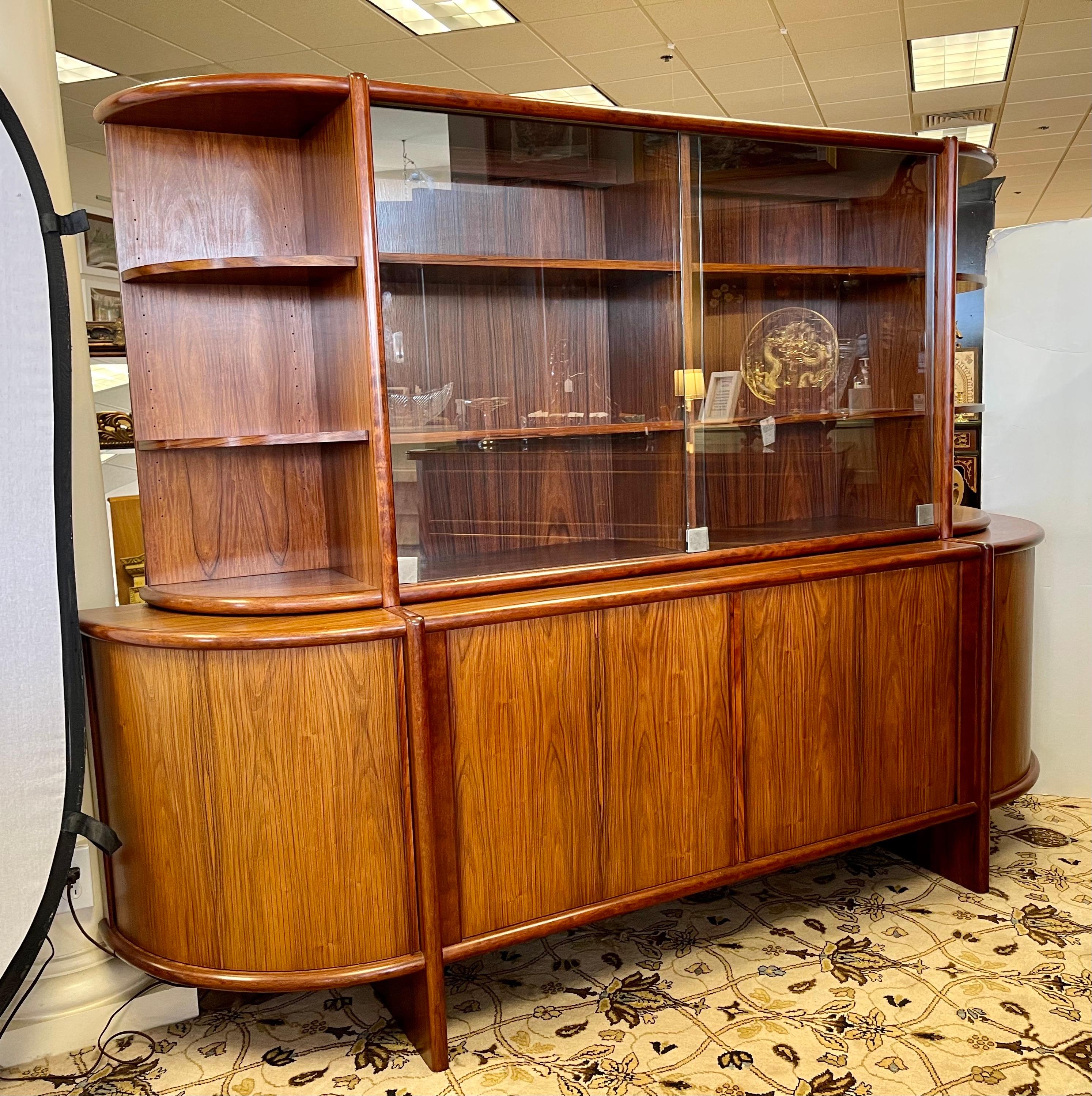 Stunning vintage Boltinge Danish modern 2 pc china cabinet credenza features upper portion with sliding glass doors and curved open shelving on the sides. Bottom credenza features sliding tambour doors that open to shelving and felt-lined drawers. A