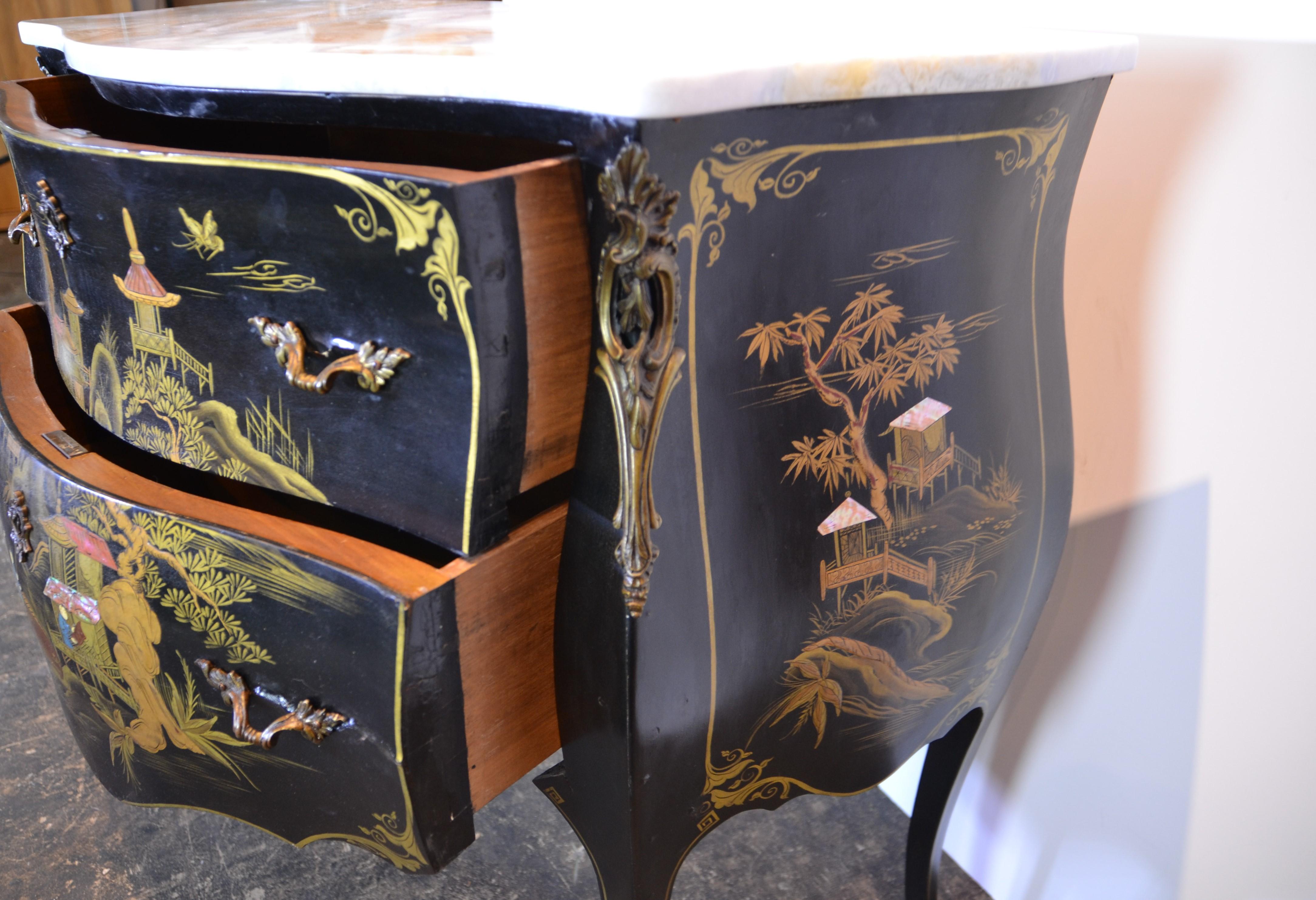 A smaller size Bombay chest of 2 drawers with hand decorated Chinoiserie to the front and sides. Bronze decorations to the feet and uprights. Bronze Keyhole Escutcheons. Replacement marble is white with gray and beige.