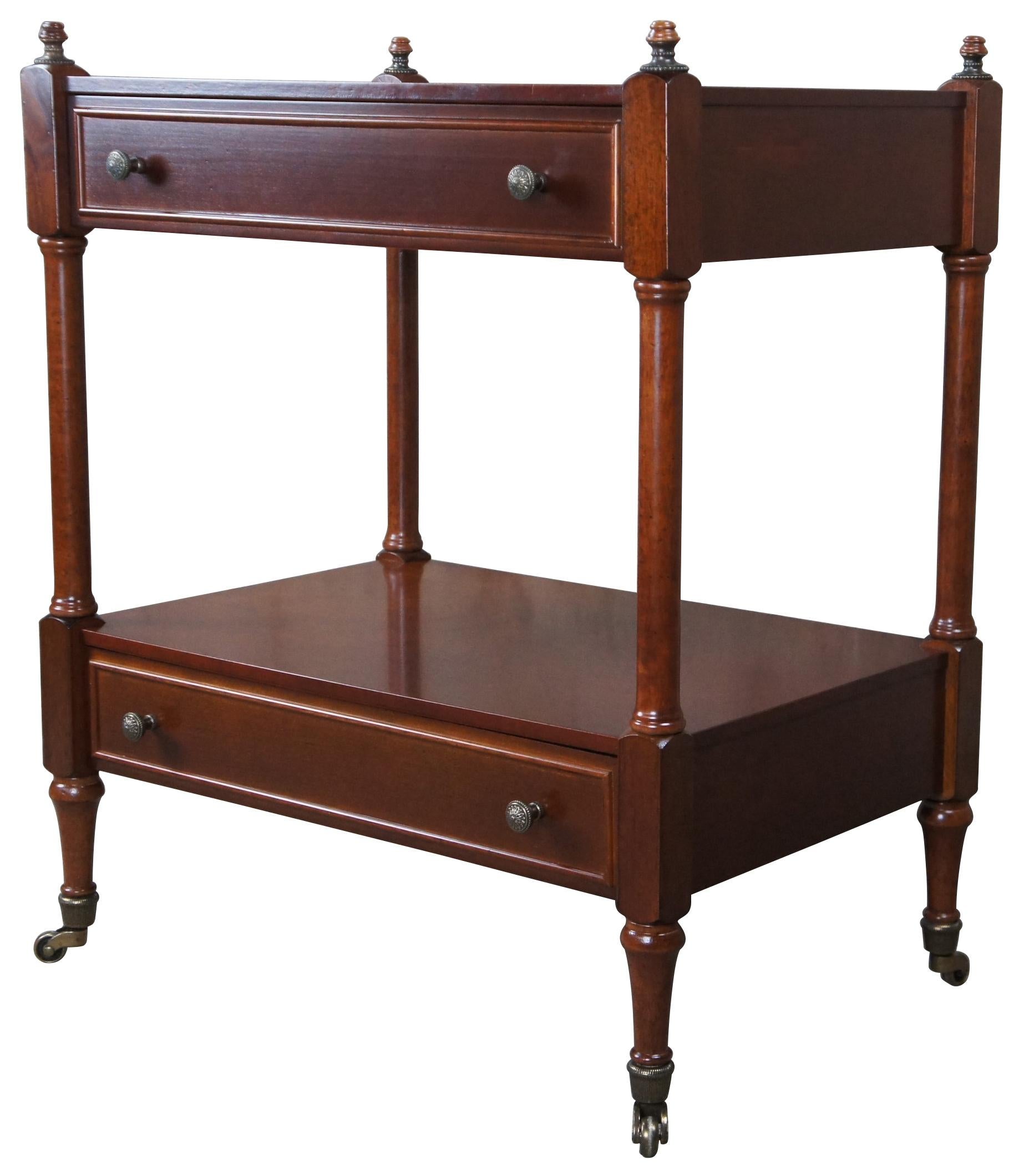 Bombay Company cherry finished side table, c. 1996. Features a 2 tier design with an upper and lower drawer. The table is accented by finials and rests on tapered legs leading to brass casters.

24.75