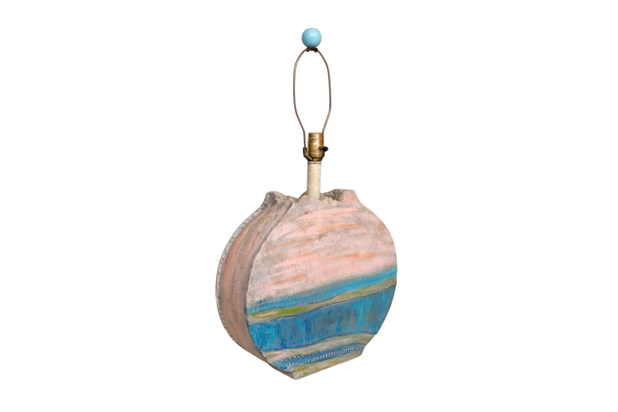 A coastal style plaster table lamp made by Bon Art. A robin's egg blue ball finial tops the harp, and a circular base is decorated with an abstract incised raised design in cerulean blue, green, and blush pink. Signed Bon Art, 1989. Measures 17.5