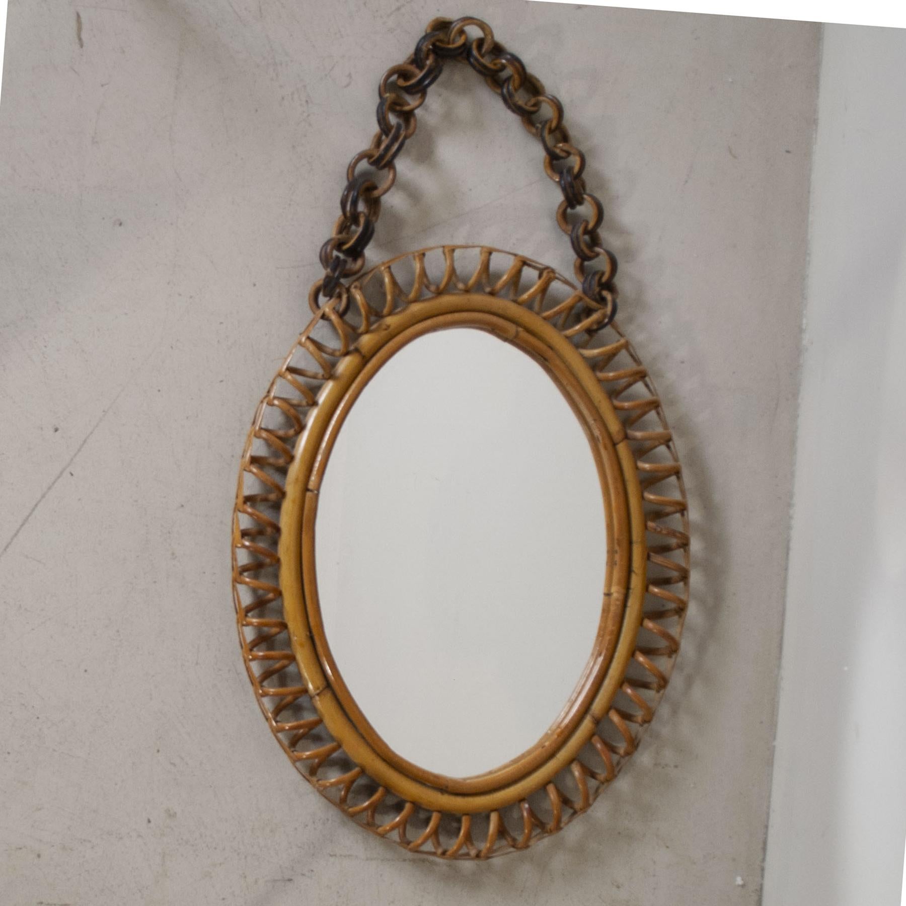 Oval mirror with curved frame and guinea cane chain manufactured by Bonacina 1960s.