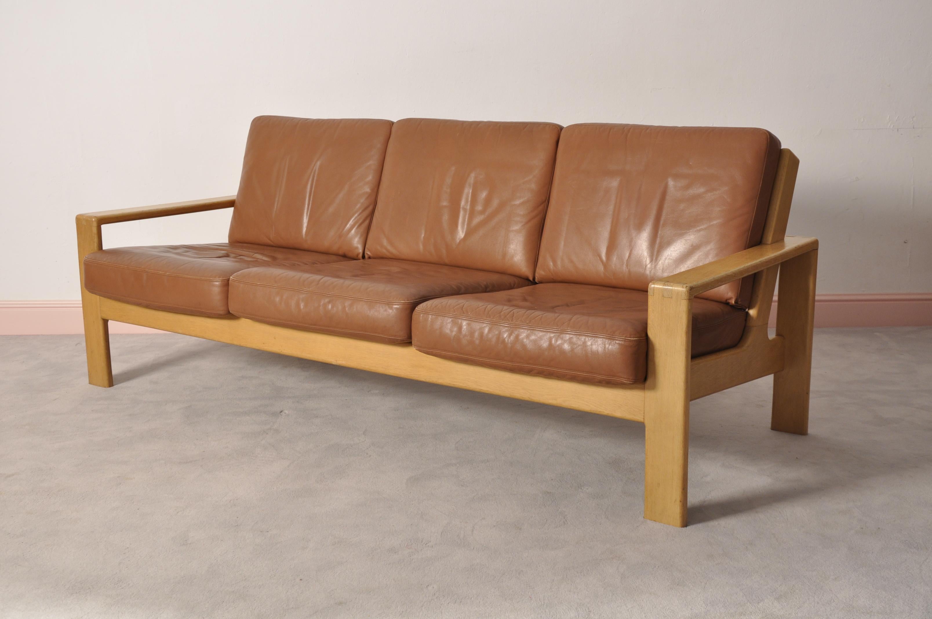 Organic Design form the late 1960s. Frame made from massive oakwood, cognac-collored leather cover. Feather filled cushions. Modern seat hight (38cm).