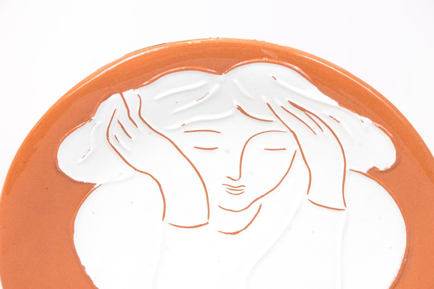 Round faience plate made by the French Artist Pierre Boncompain (1938 - ). 
The plate represents a white woman on an ochre background, she is holding her head, looking dreamy, and below her, three small lemons.
On the back, stamp of the artist and