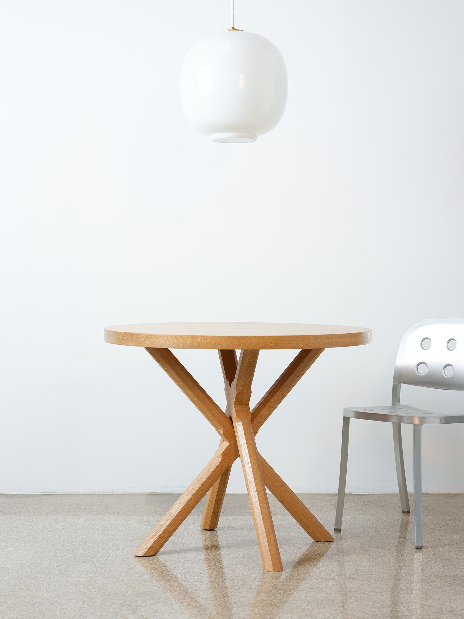 This modern compact pedestal table features all-hardwood construction. The chunky table top sits atop an X-shaped base with intricately carved polygonal legs. The legs are two separate components making it easy to disassemble, pack, and transport.